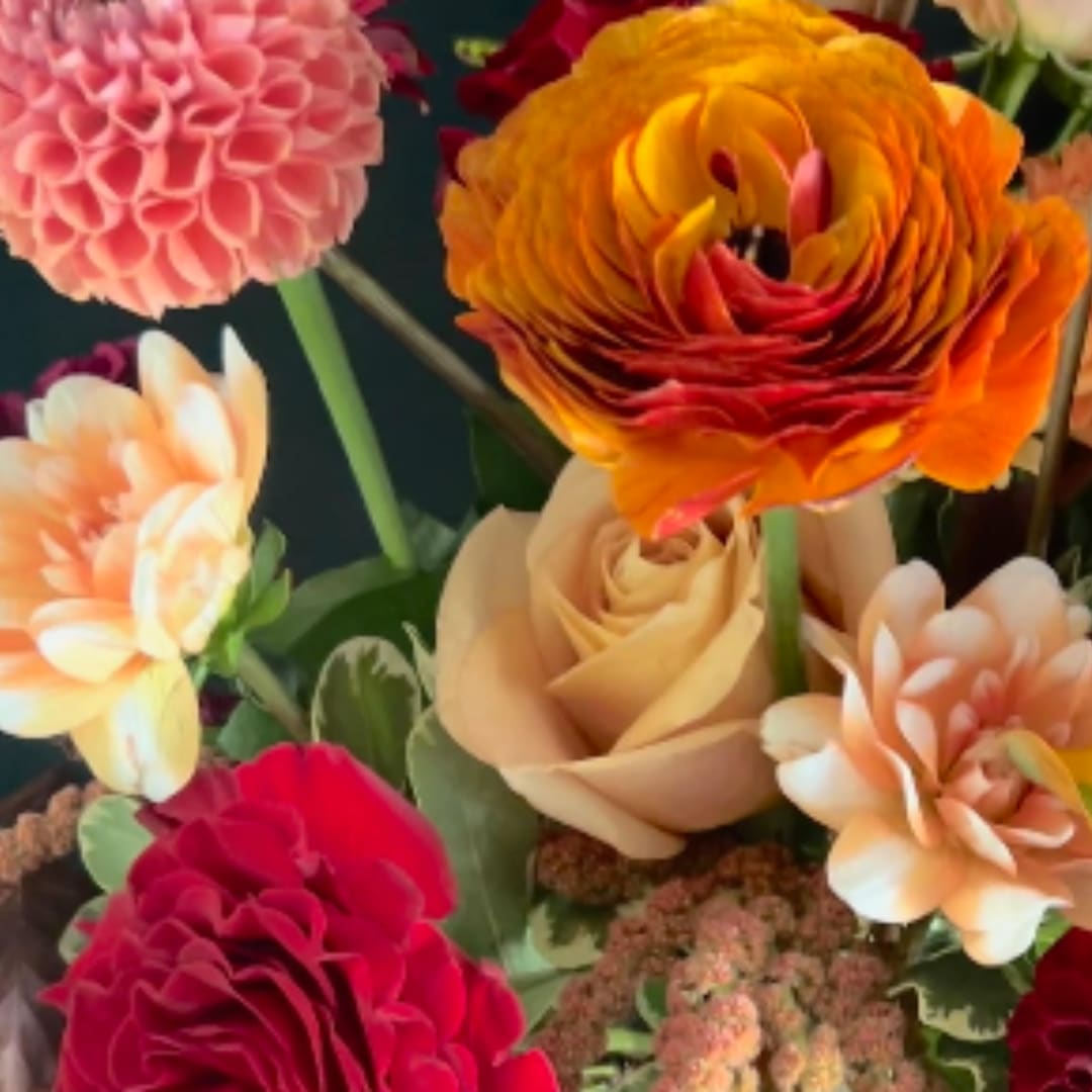 Close-up of colorful mixed flowers including dahlias, roses, and ranunculus