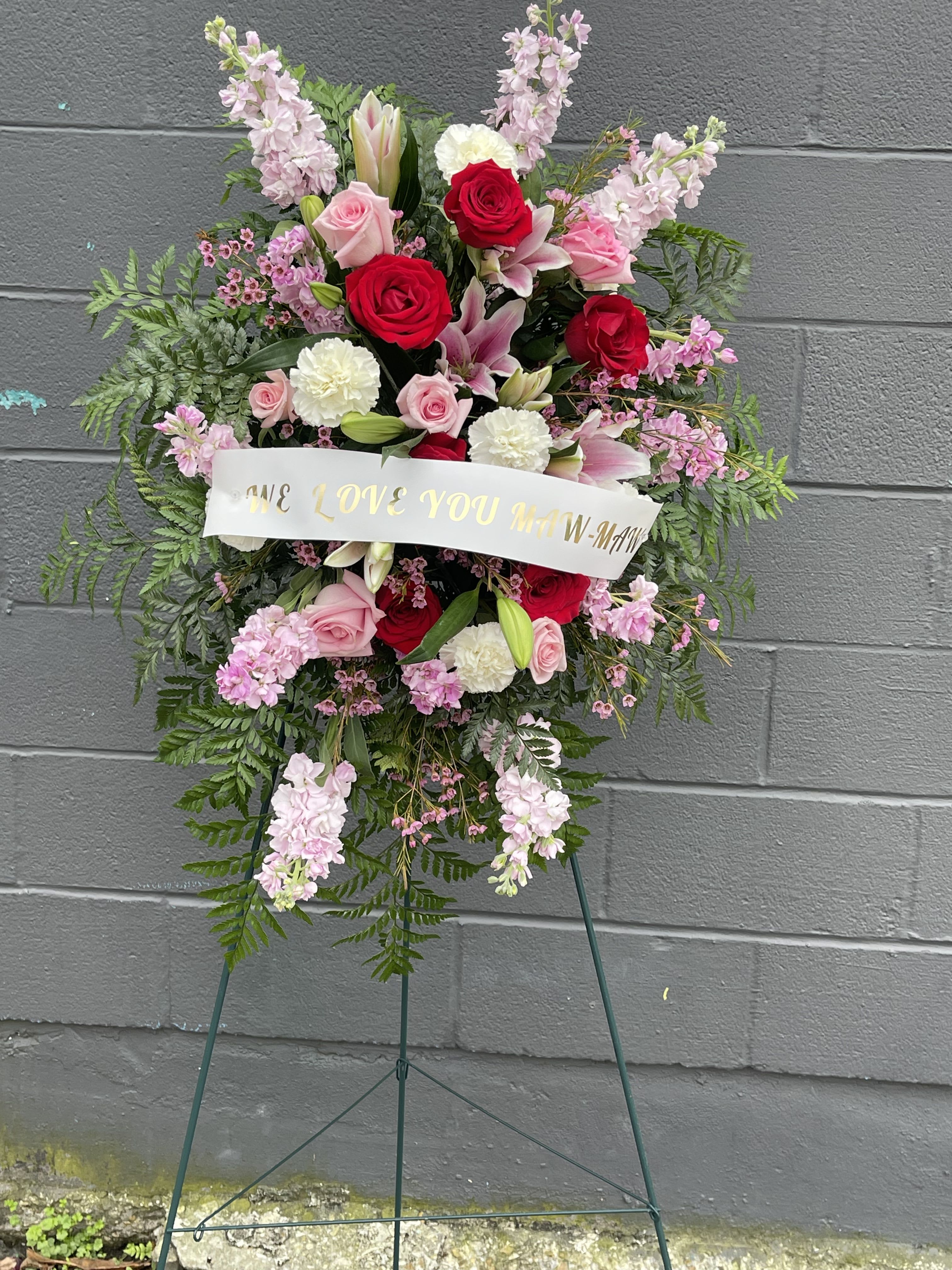 The beautiful touches of pink memory standing spray  - This beautiful spray is created with roses, lilies, carnations, wax flowers and a variety of flowers and we can customize the banner please let us know what you would like your message to say in comments section 