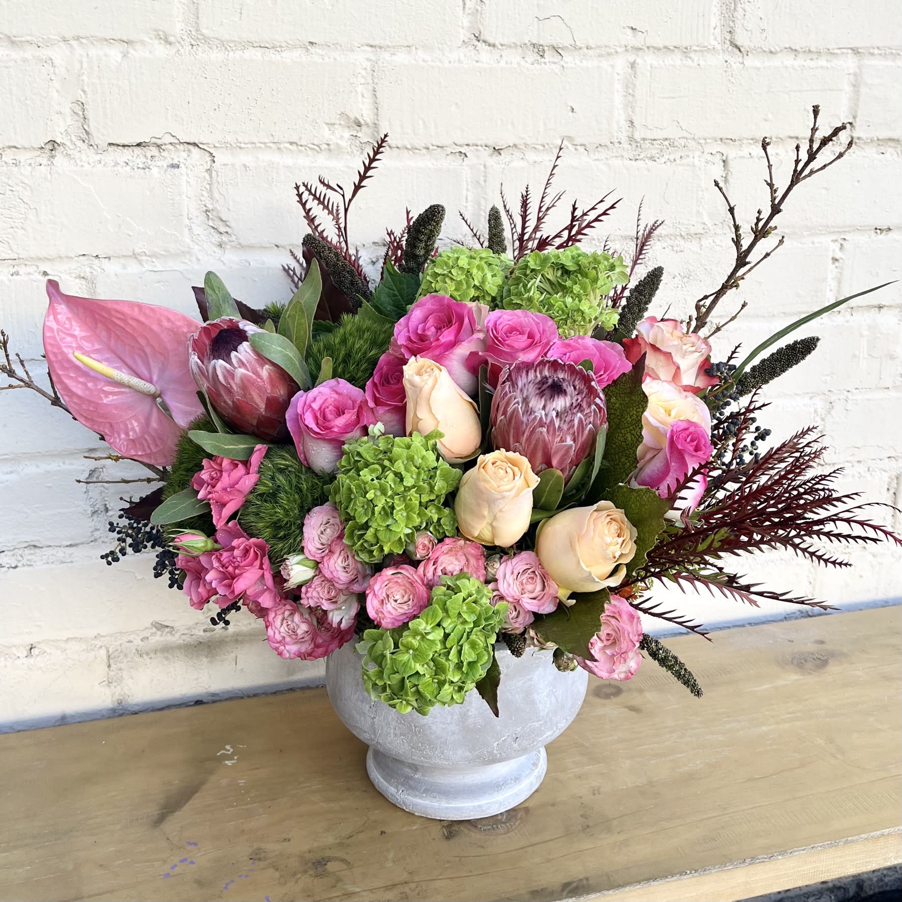 Pink and cream floral arrangement in a white pedestal vase