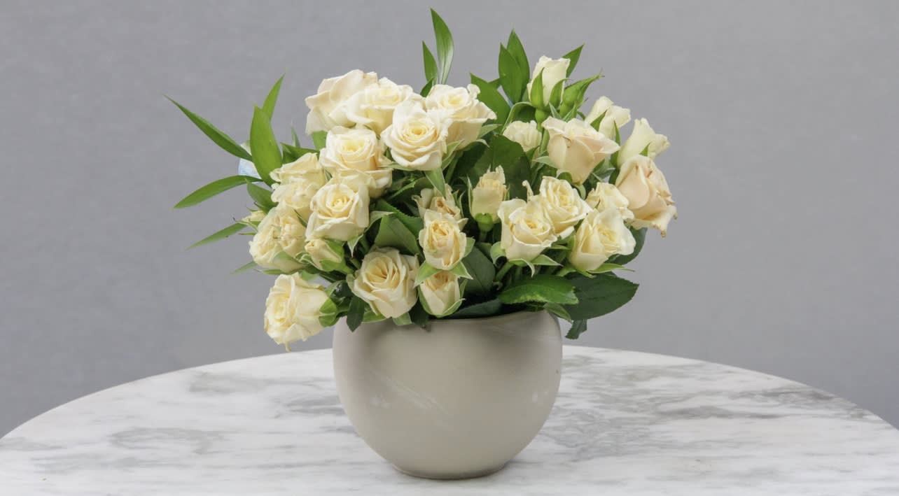 Cream rose bouquet in a round white vase