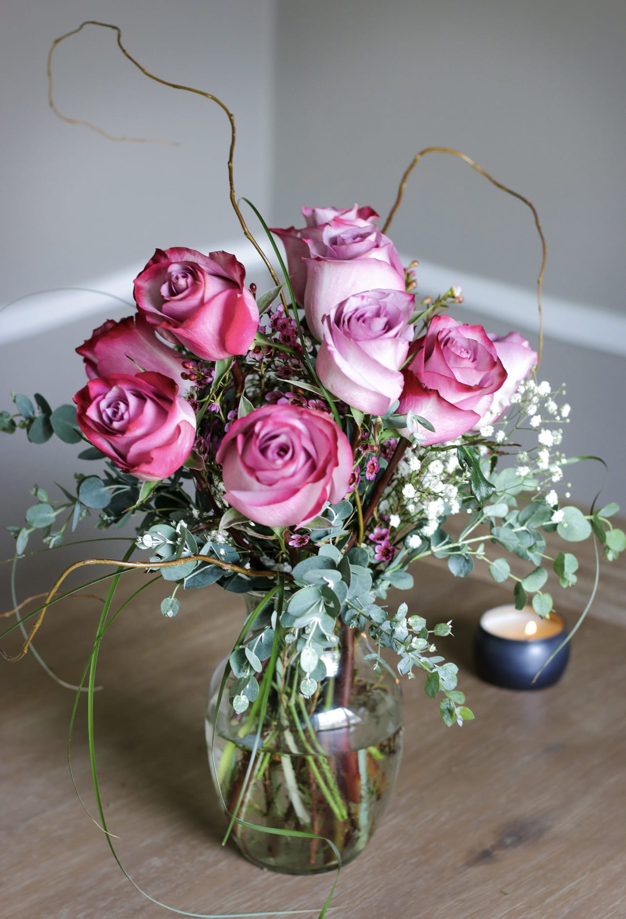 Pink roses arranged in a glass vase with airy filler flowers