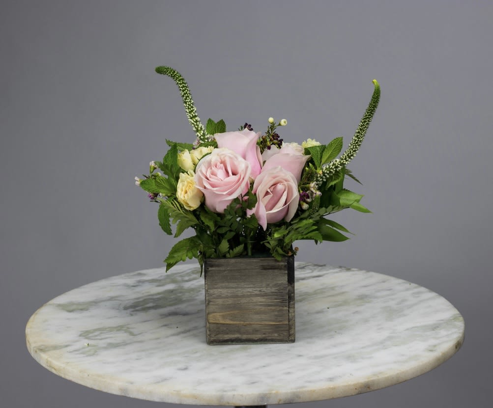 Pink roses in a wooden box with greenery and tall accent stems