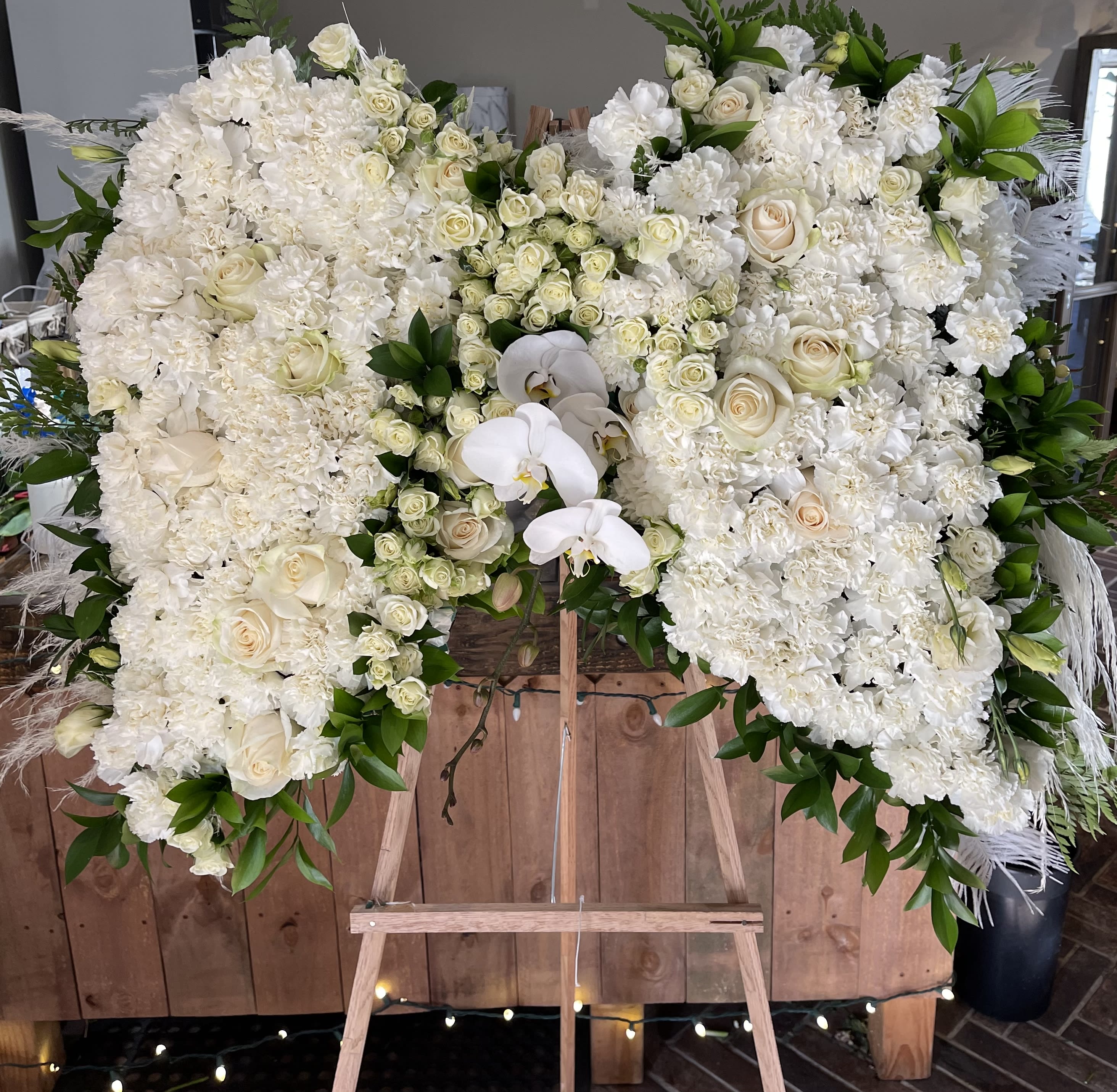 Large white floral spray on an easel with roses and orchids
