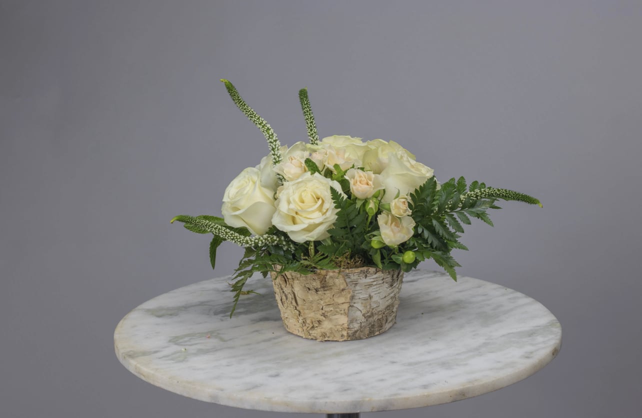 Cream rose arrangement in a birch bark container