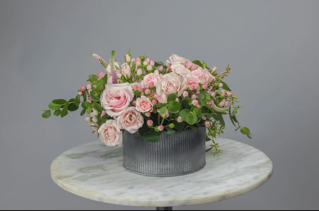 Pink roses and small blossoms in a gray ribbed container