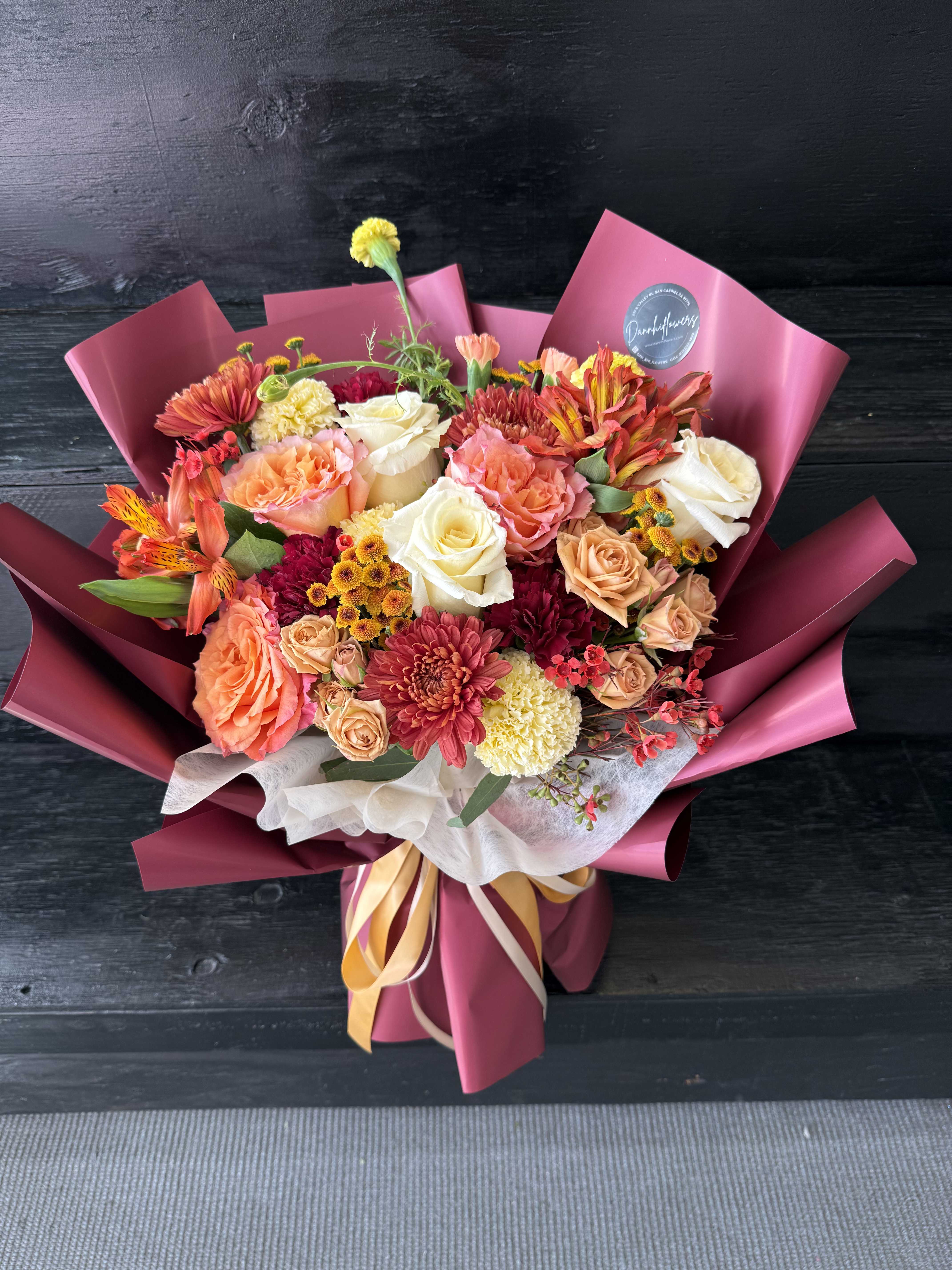 Mixed bouquet of roses, chrysanthemums, and alstroemeria wrapped in pink paper