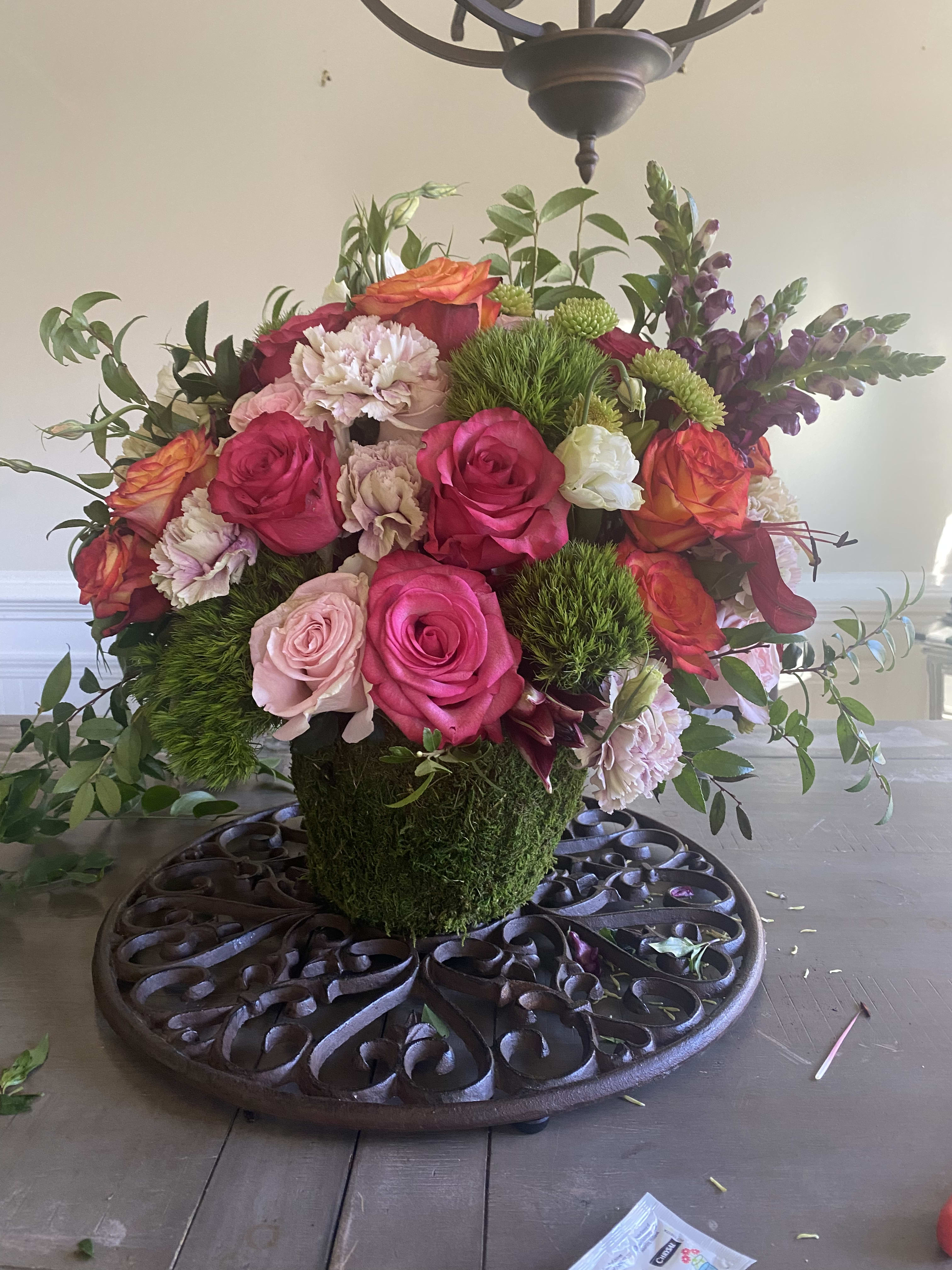 TowneLake Gardens  - If you love the feel of rose garden, the Tisch Garden will literally excite your tablescape! Tisch will have 18-36 roses coloring pinks, oranges &amp; jewel tones with seasonal fillers in a green moss container. Get ready to enjoy an instant garden!  * Premium Shown Standard has 18 roses with more seasonal greenery Deluxe has 24 roses with more seasonal greenery 