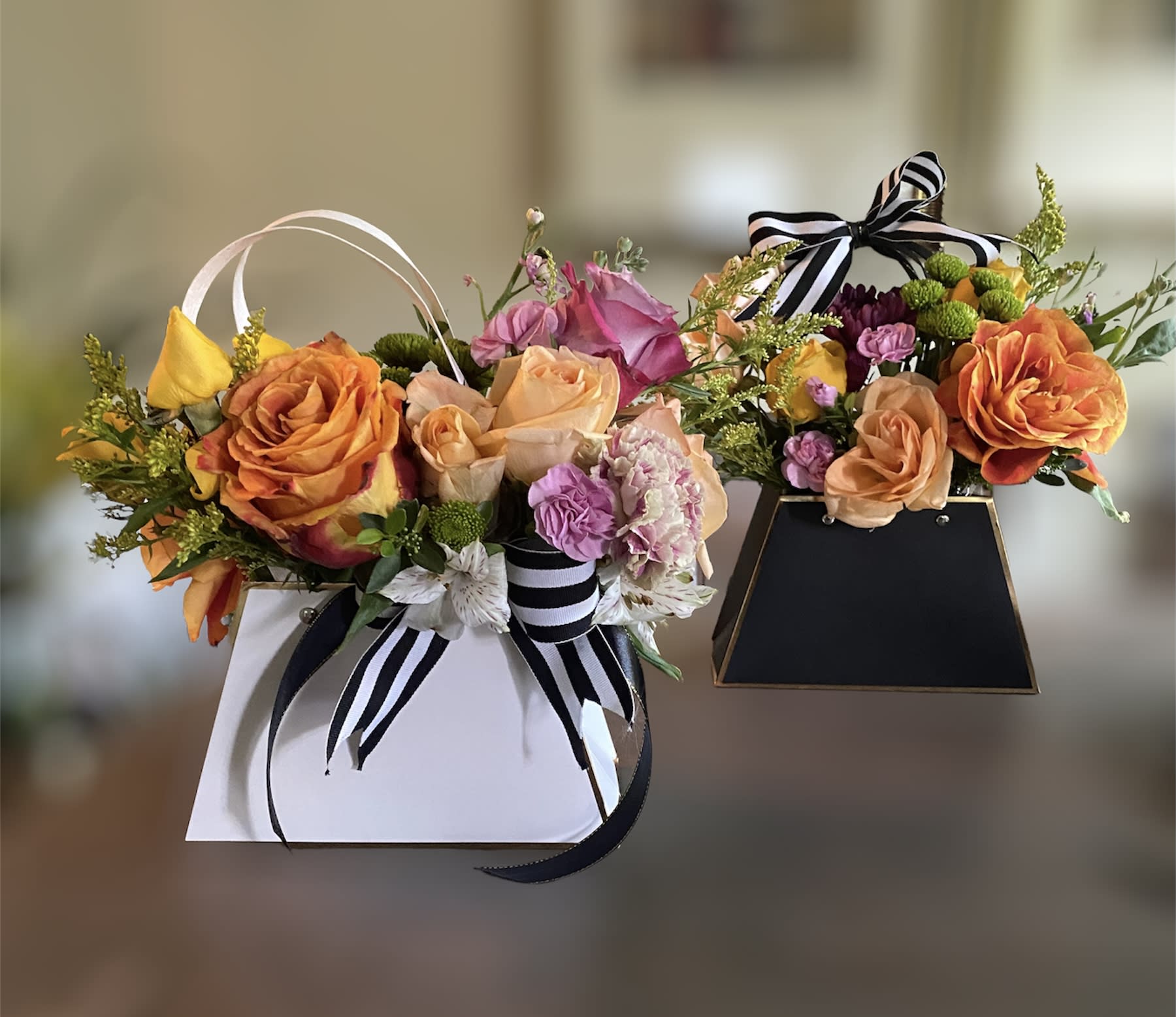 Queenie’s - Have a favorite duo in mind? Why not purchase the Flower Lady purses. They all come in sets of two..perfect for those who like to knock out two birds with one stone.   Each purse will contain our seasonal florist choice of roses  and fillers. Purse come in black, pink or white (shown).   Purses will be filled as a florist choice with our seasonal freshest florals and greeneries. We guarantee each purse will be slightly unique from the other with just the perfect pop of color and pizazz!