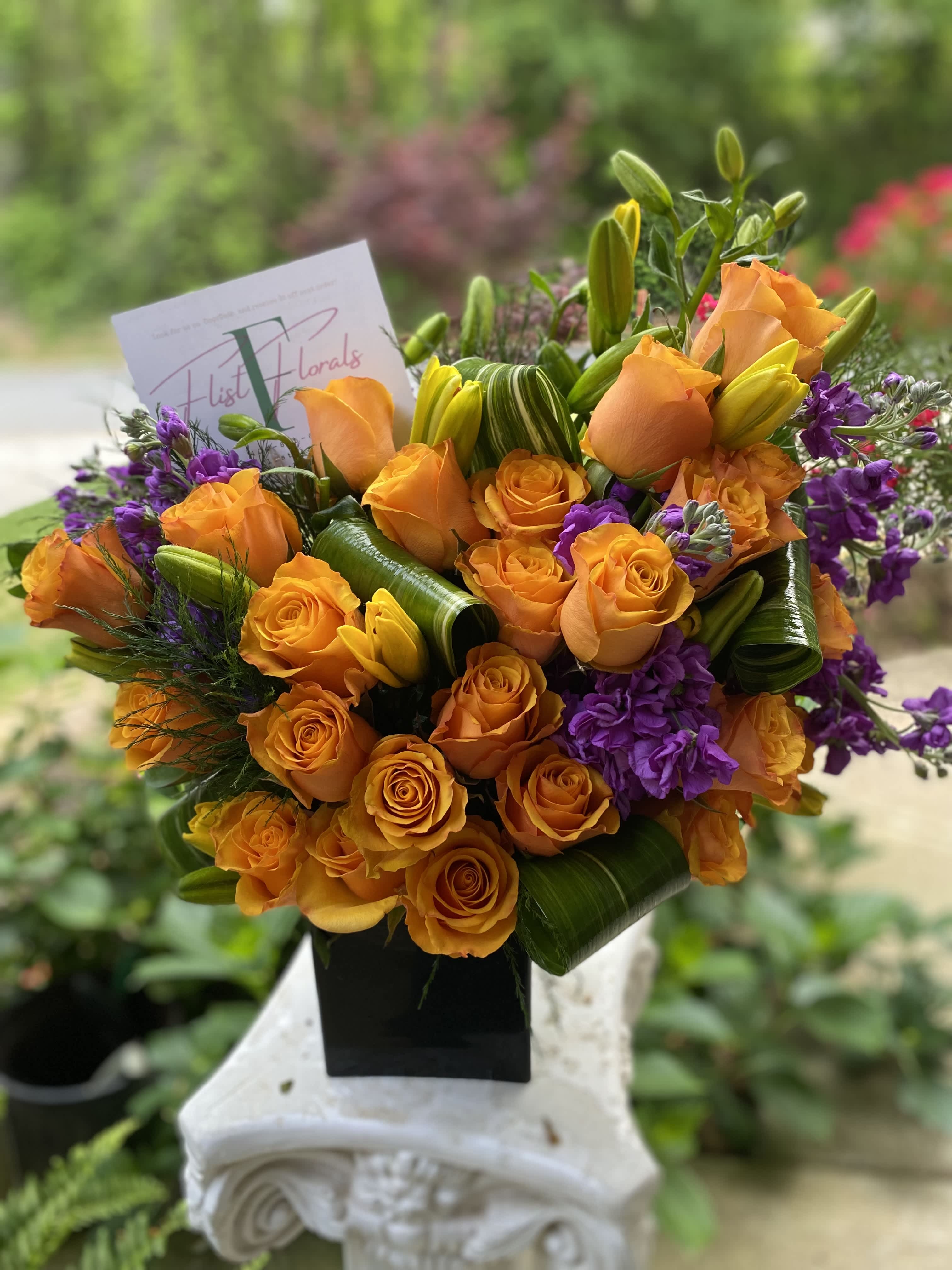 The Woodstock - Perfect arrangement for the masculine one in your life. It’s structure of orange roses paired with asiatic Lillies and hot pink carnations will give the right amount of flare and aroma to brighten up your loved one’s space.