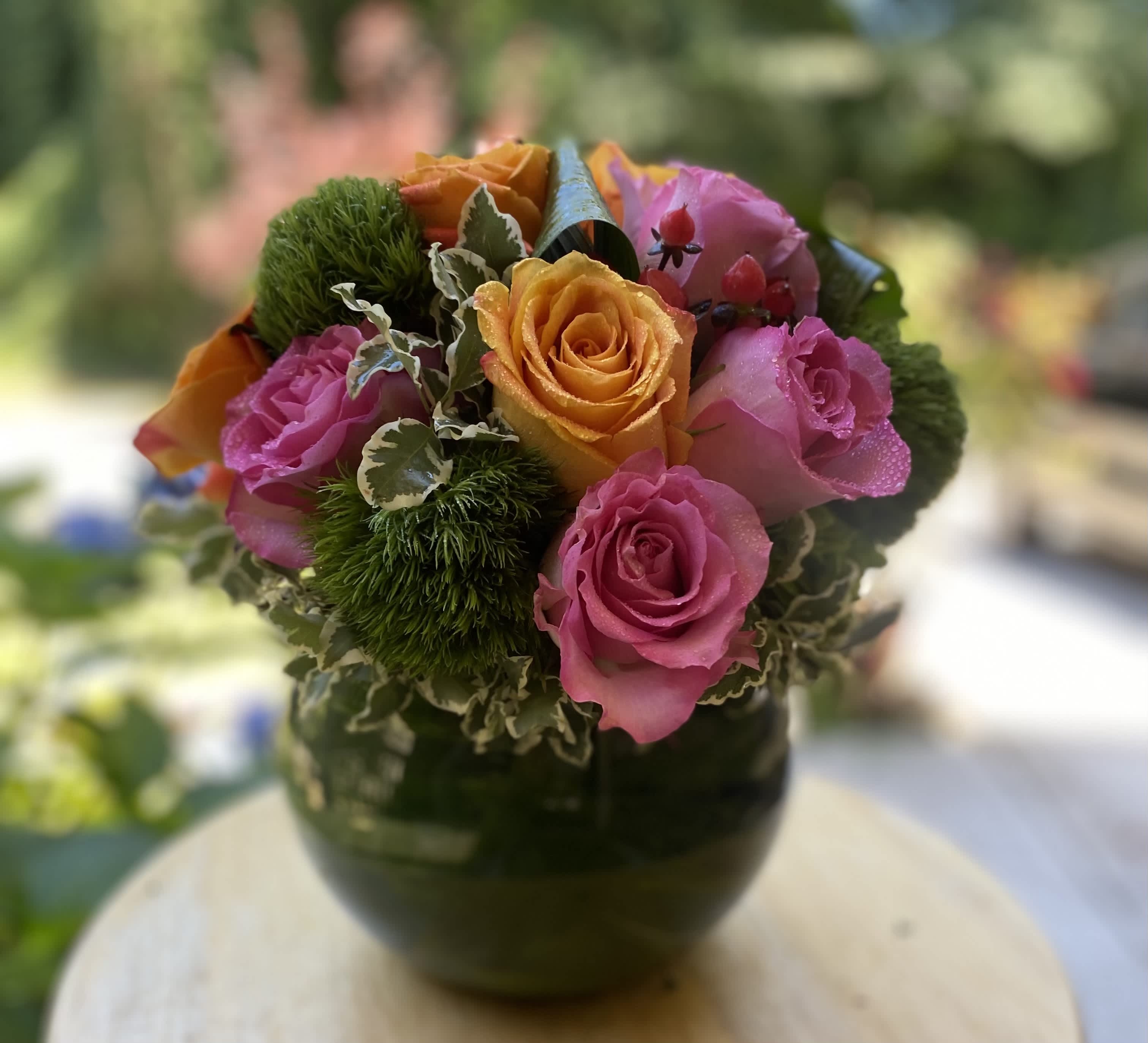 BallGround Beauty - Brighten any space with this vibrant floral arrangement featuring bold orange and pink roses, lush greenery, and unique accent textures, all displayed in a charming green glass vase. This eye-catching design is perfect for sll celebrations, or adding a pop of color to your home or office. Handcrafted with care by Flist Florals, serving Canton, Woodstock, Kennesaw, Roswell, and the Atlanta area with stunning, custom floral arrangements. Experience the beauty of fresh flowers delivered with a personal touch.   Standard- 5-6 inch vase  Premium-8 inch vase (shown)