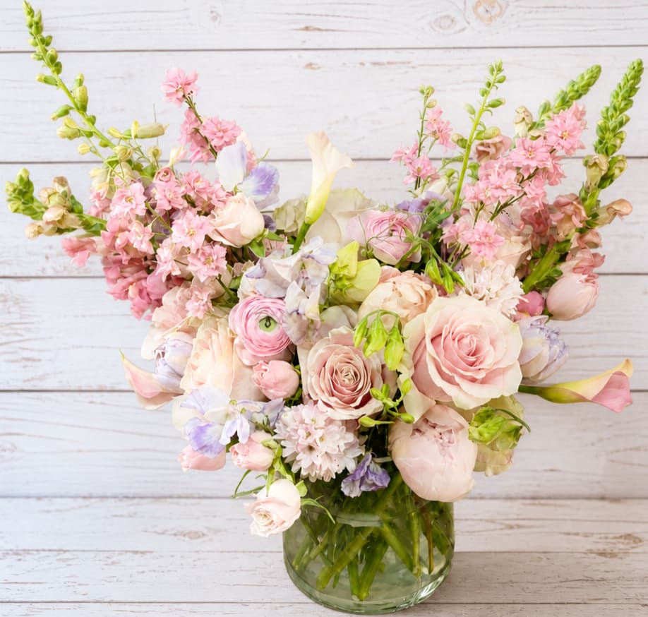 Pastel bouquet of roses, calla lilies, and mixed blooms in a glass vase