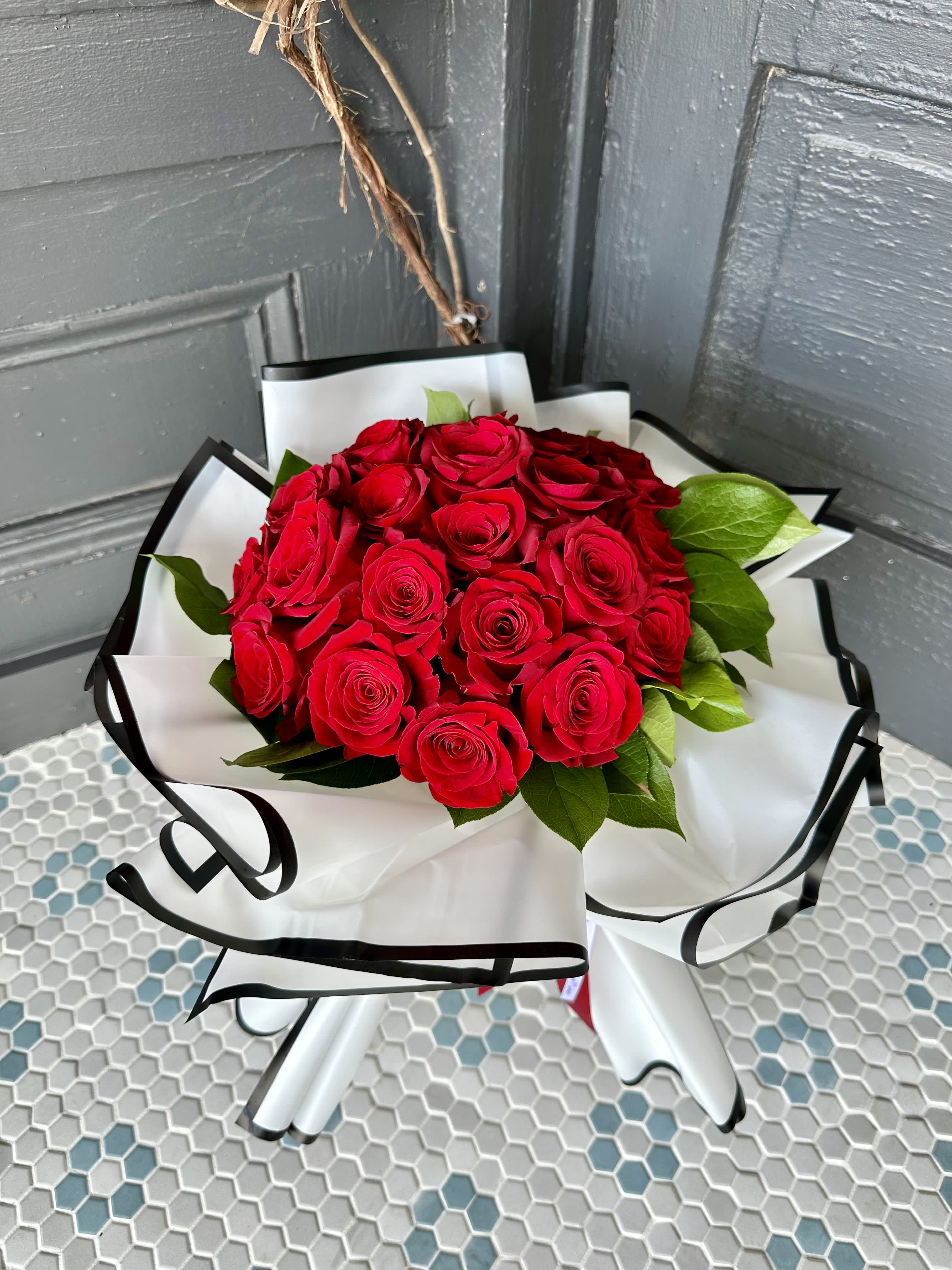 Bouquet of red roses wrapped in white paper with black trim
