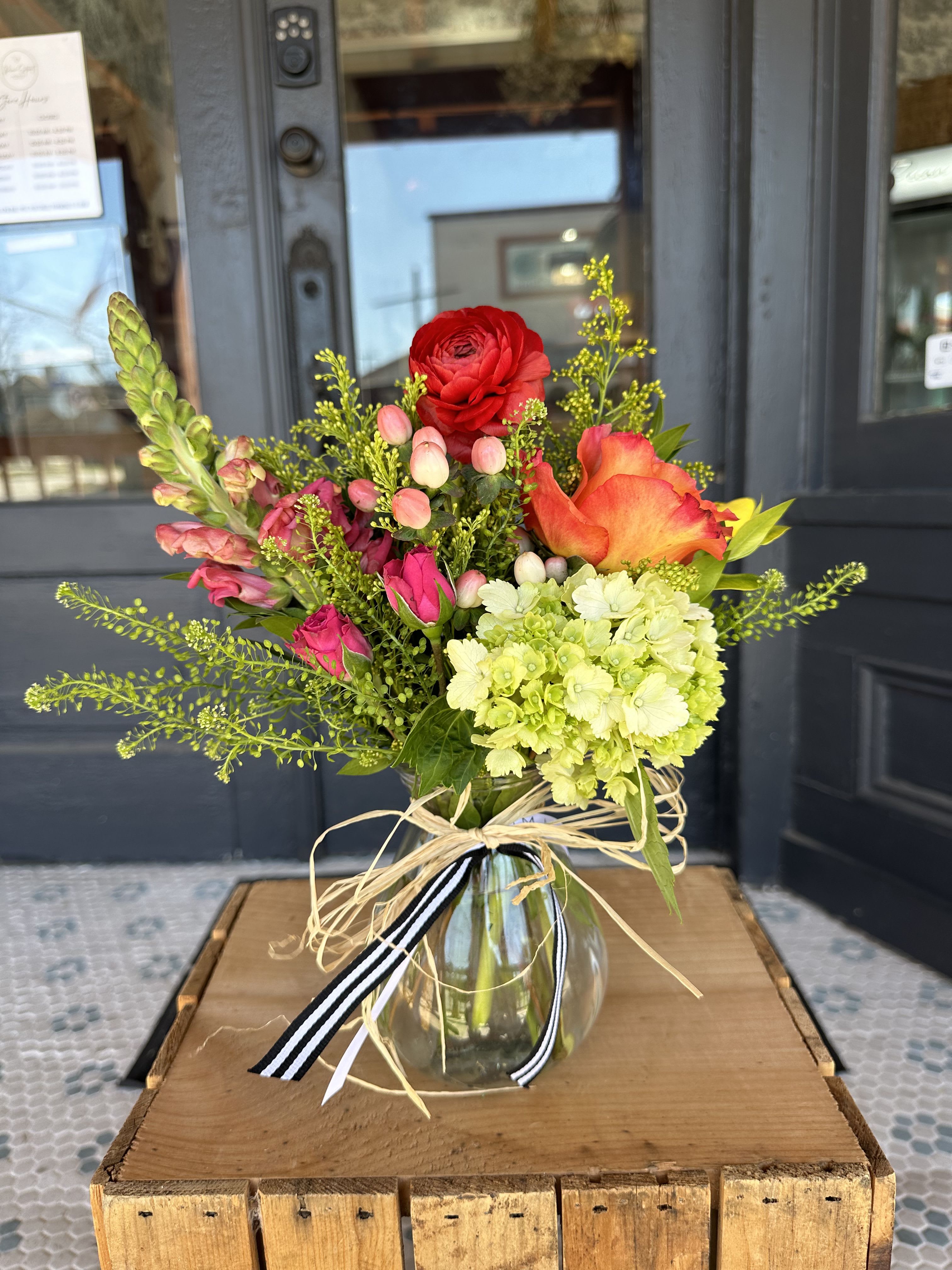 Mixed bouquet in a glass vase with red, orange, pink, and green blooms
