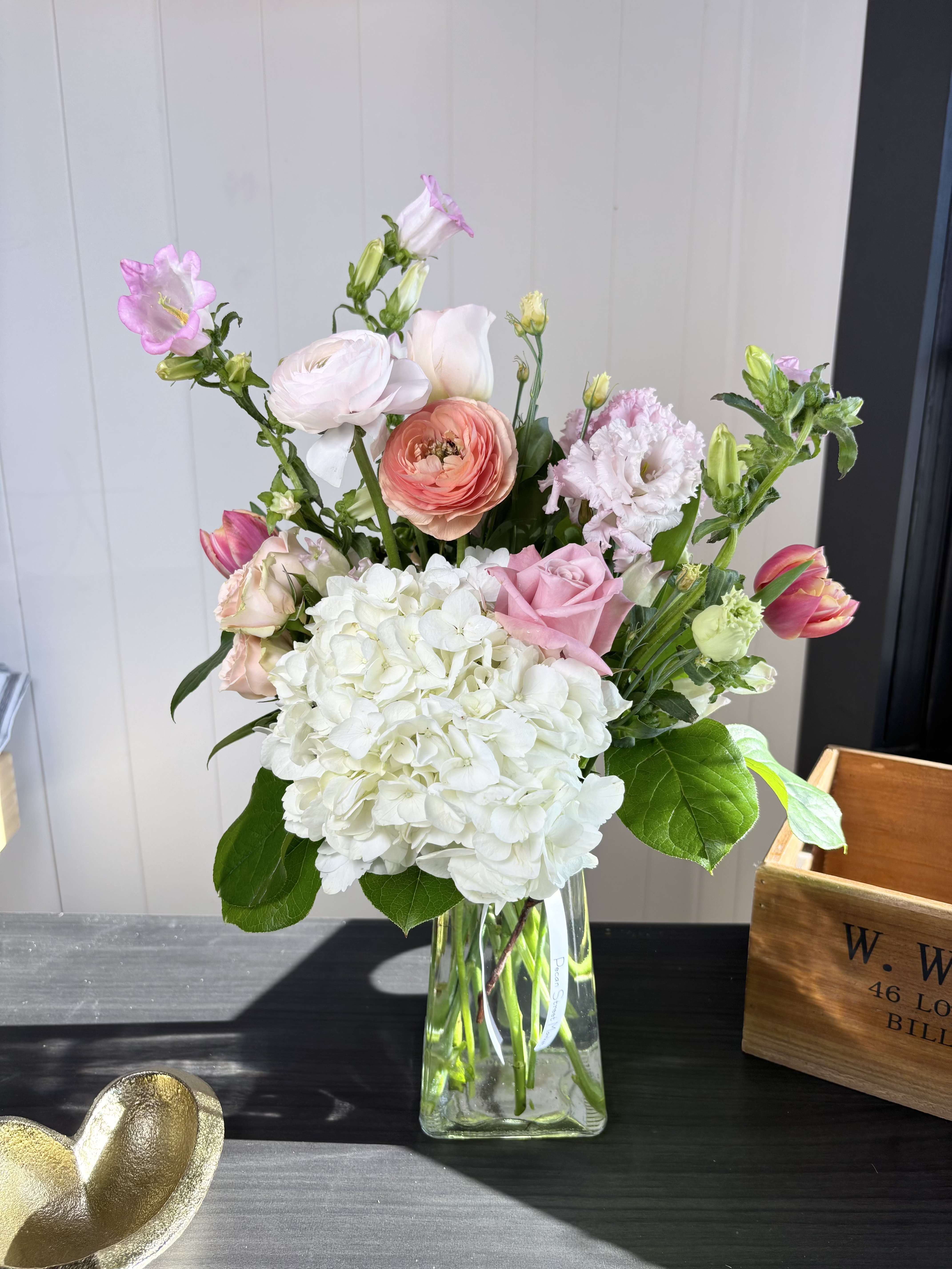 Mixed pink and white flowers arranged in a clear glass vase