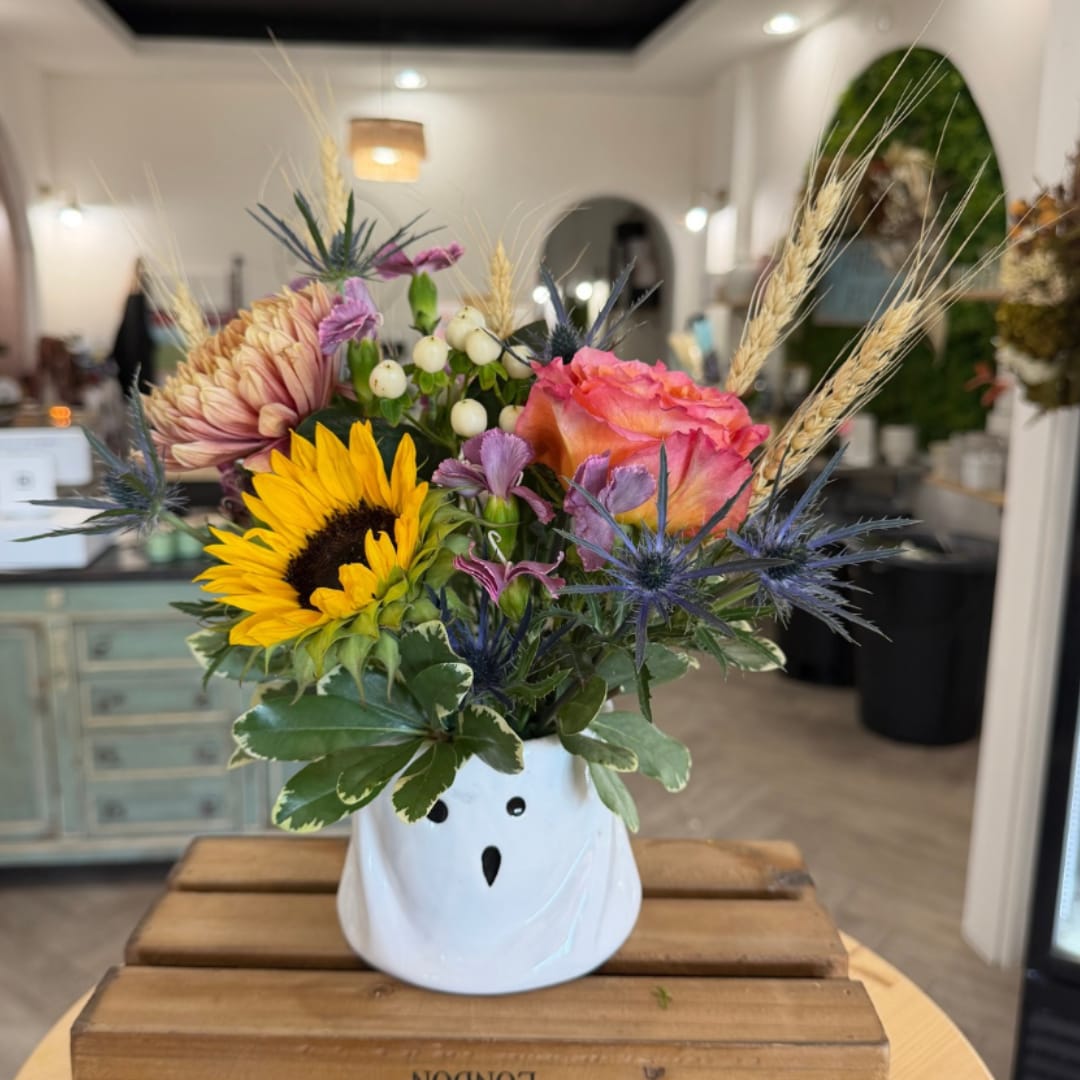 Mixed bouquet in a white ghost-shaped vase with sunflowers and roses