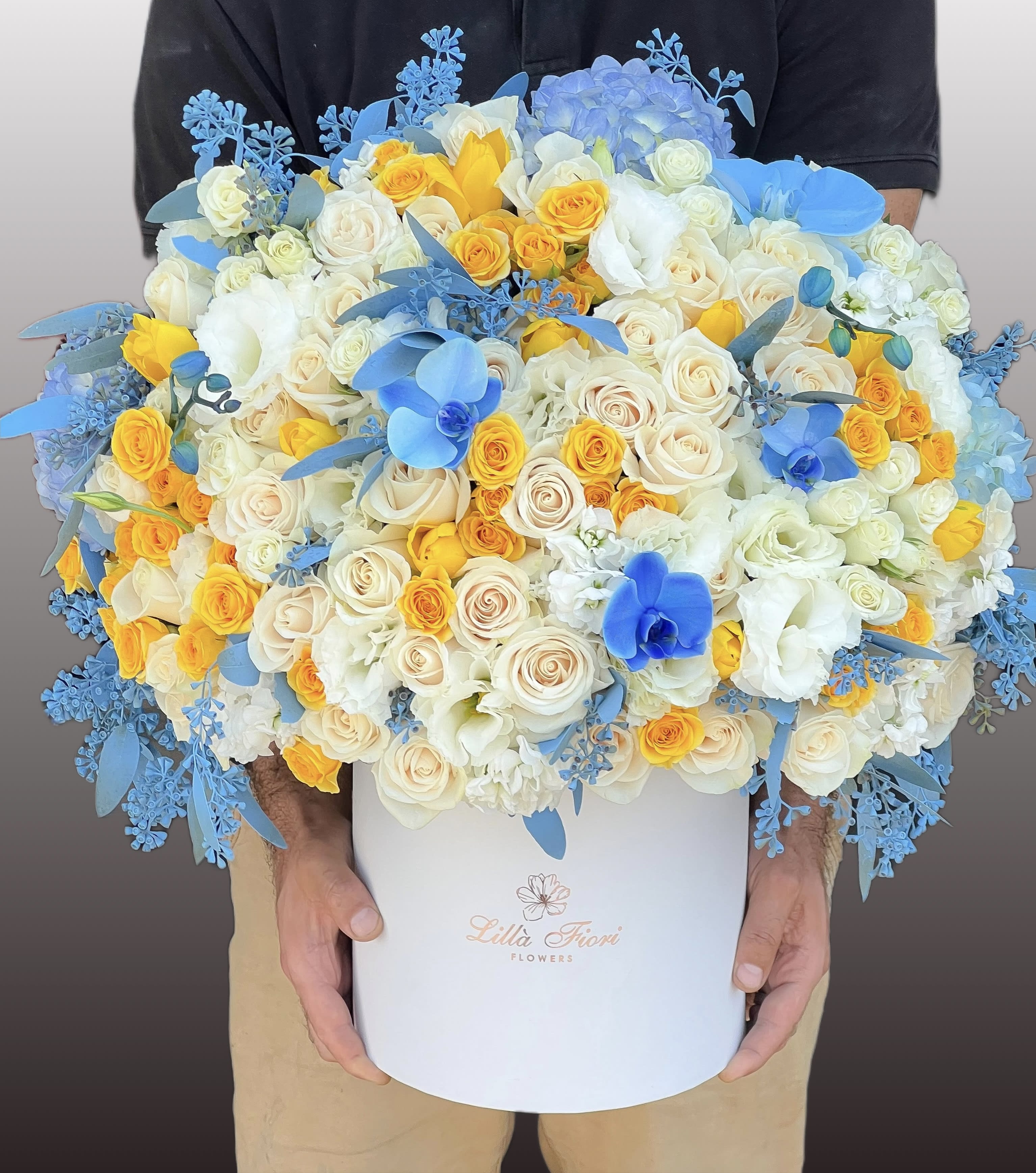 Large bouquet of white, yellow, and blue roses in a white box