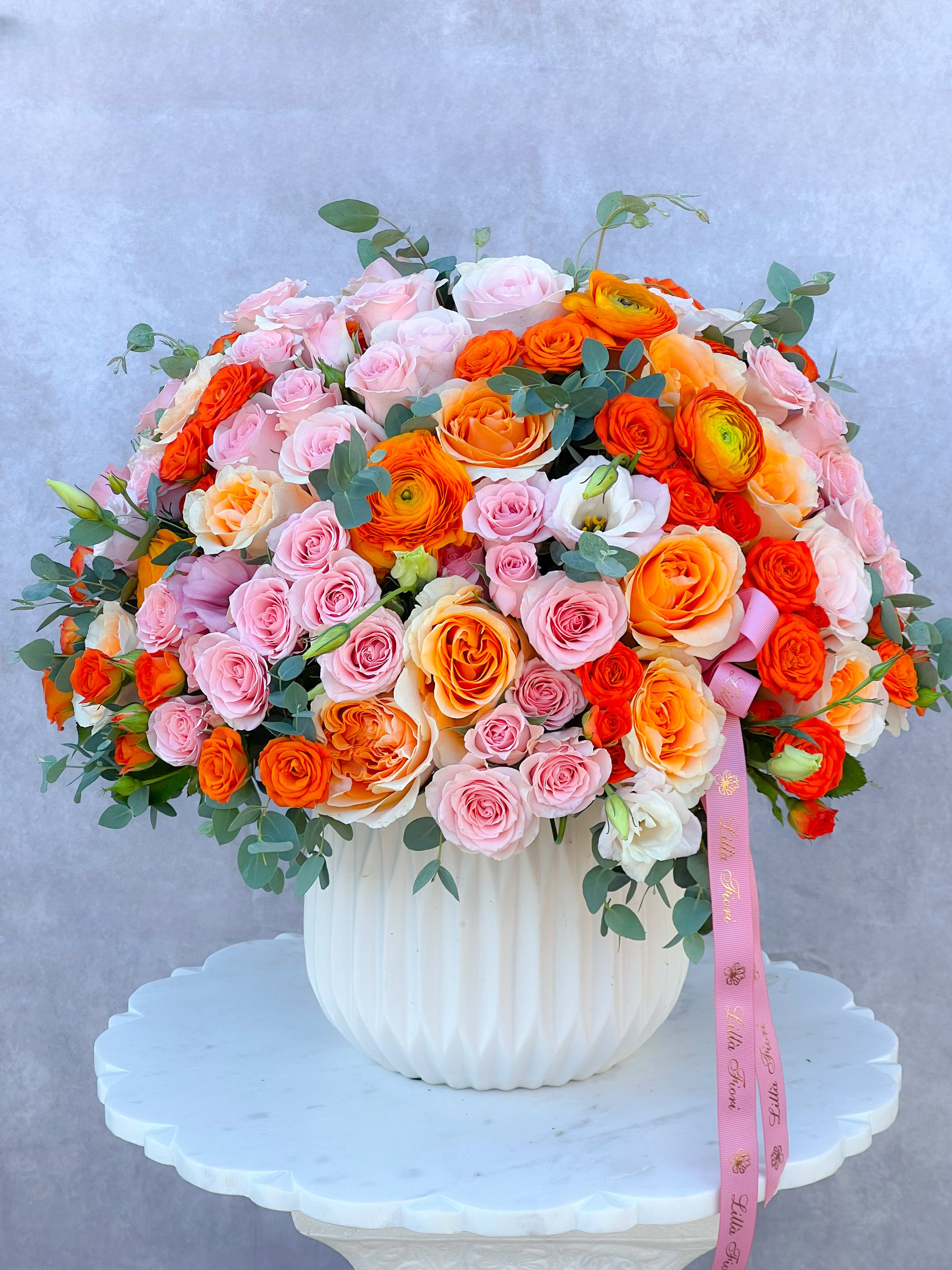 Large bouquet of pink and orange roses in a white vase