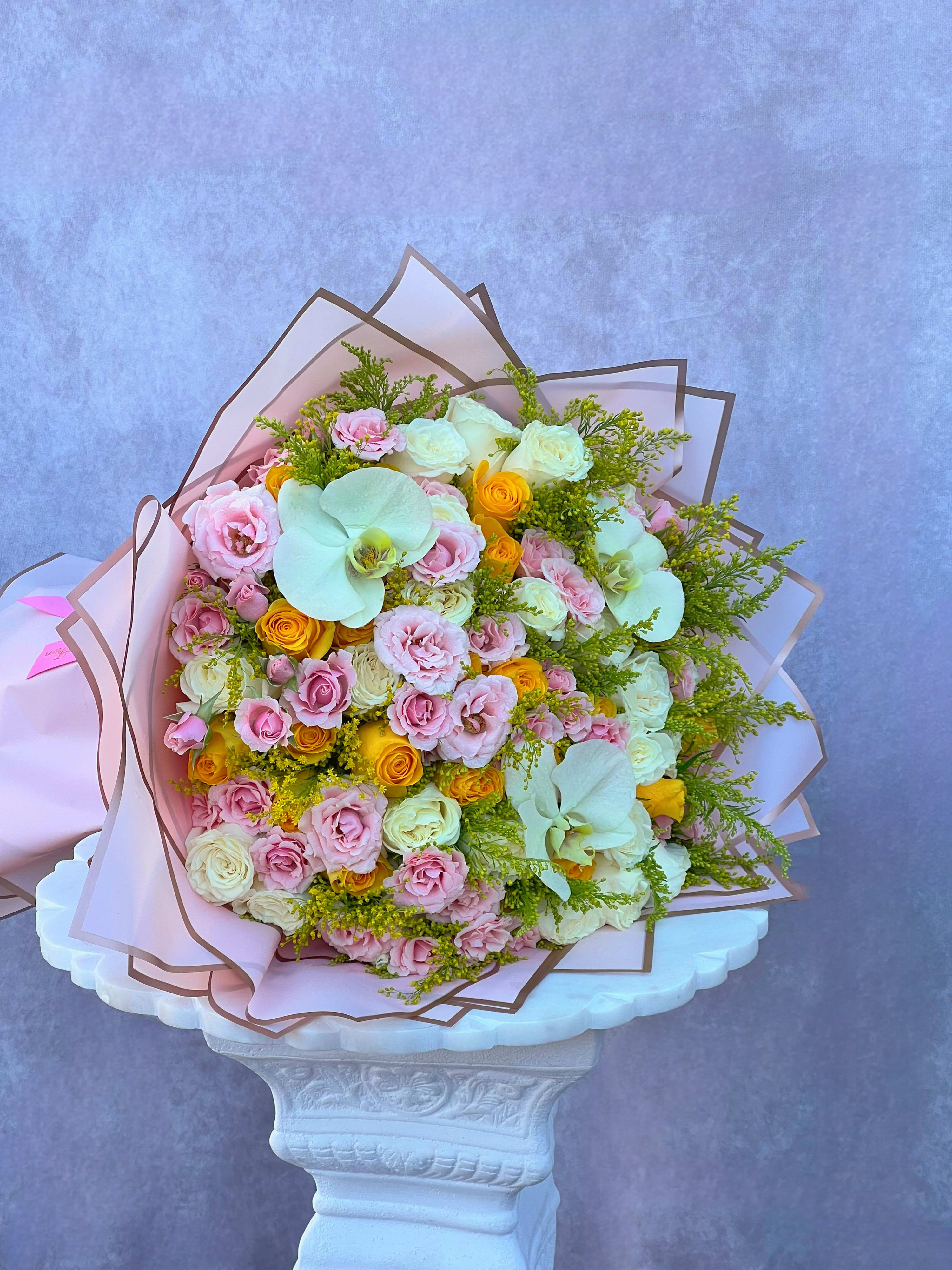 Large bouquet of pink and white roses with pale orchids and yellow accents