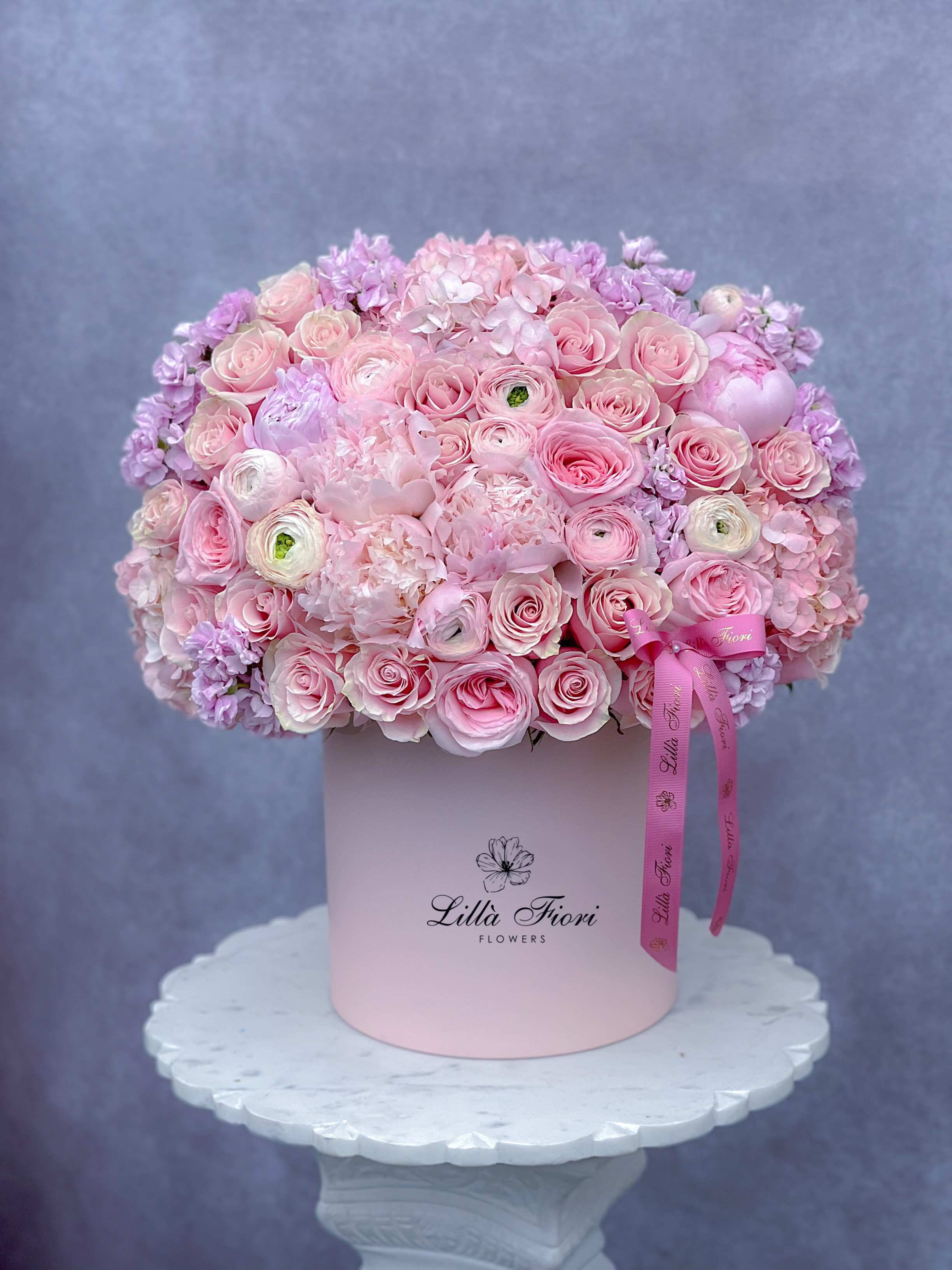 Pink rose and hydrangea arrangement in a round hat box with ribbon