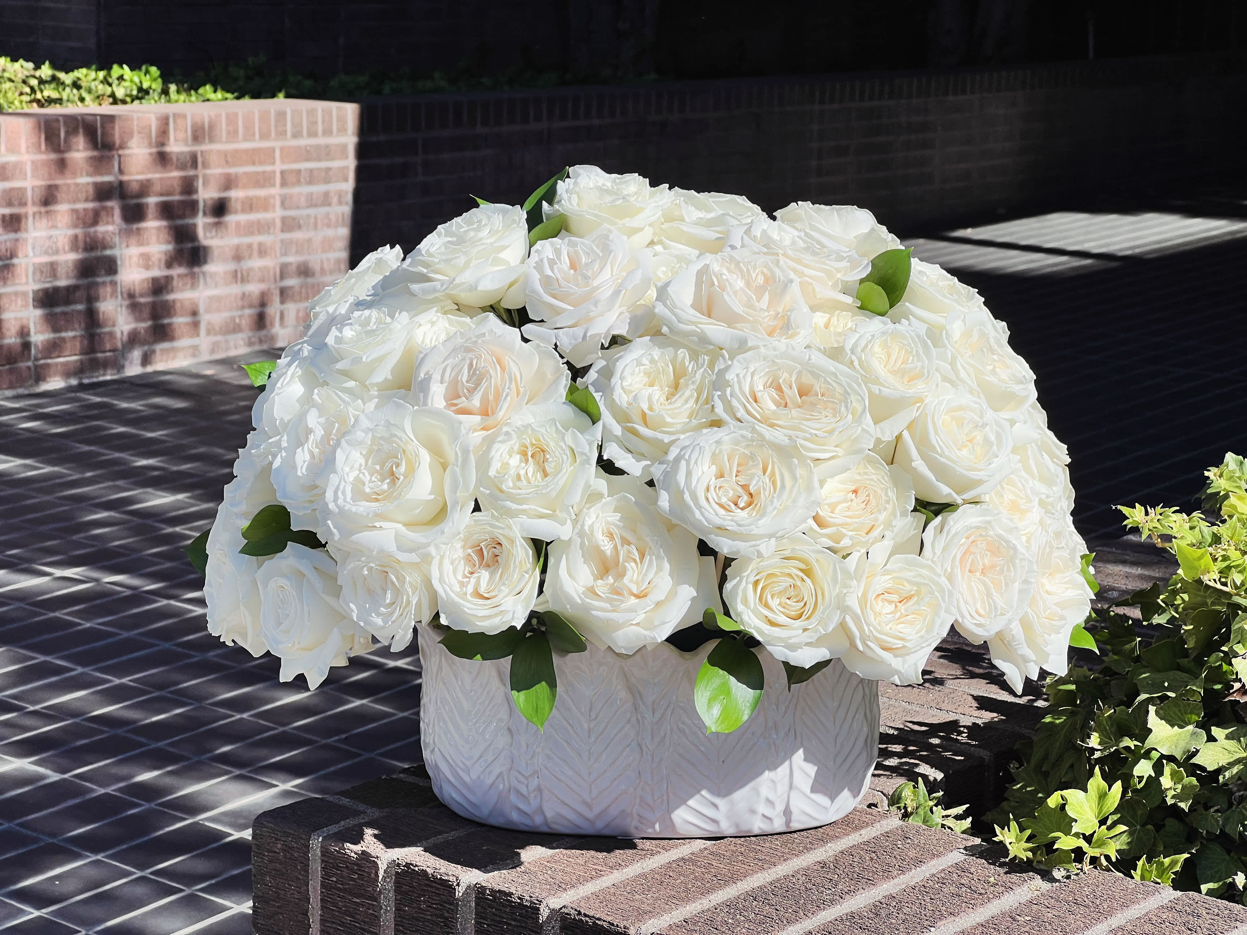 White rose arrangement in a textured white vase