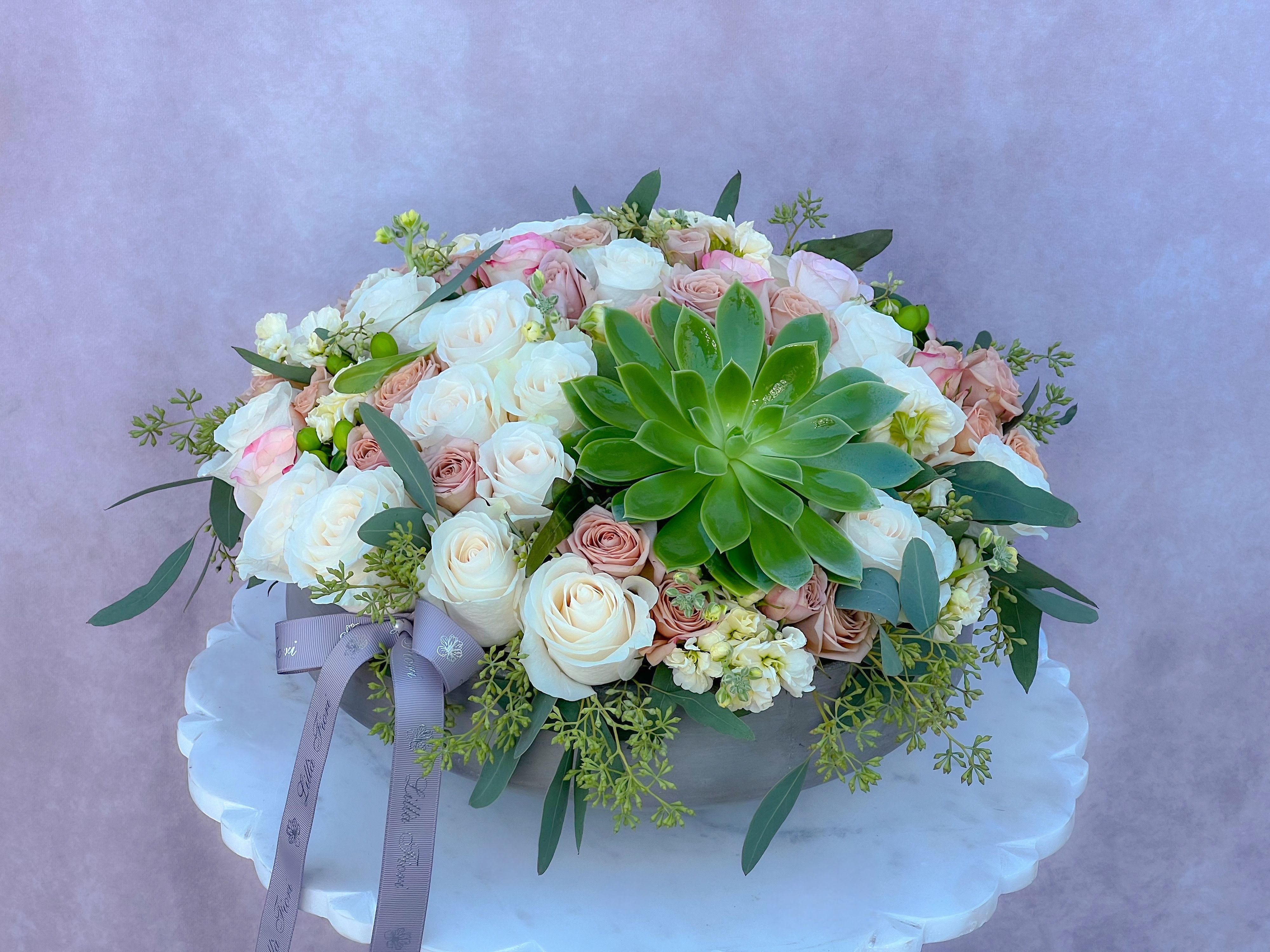 Round bouquet of white and blush roses with a green succulent centerpiece