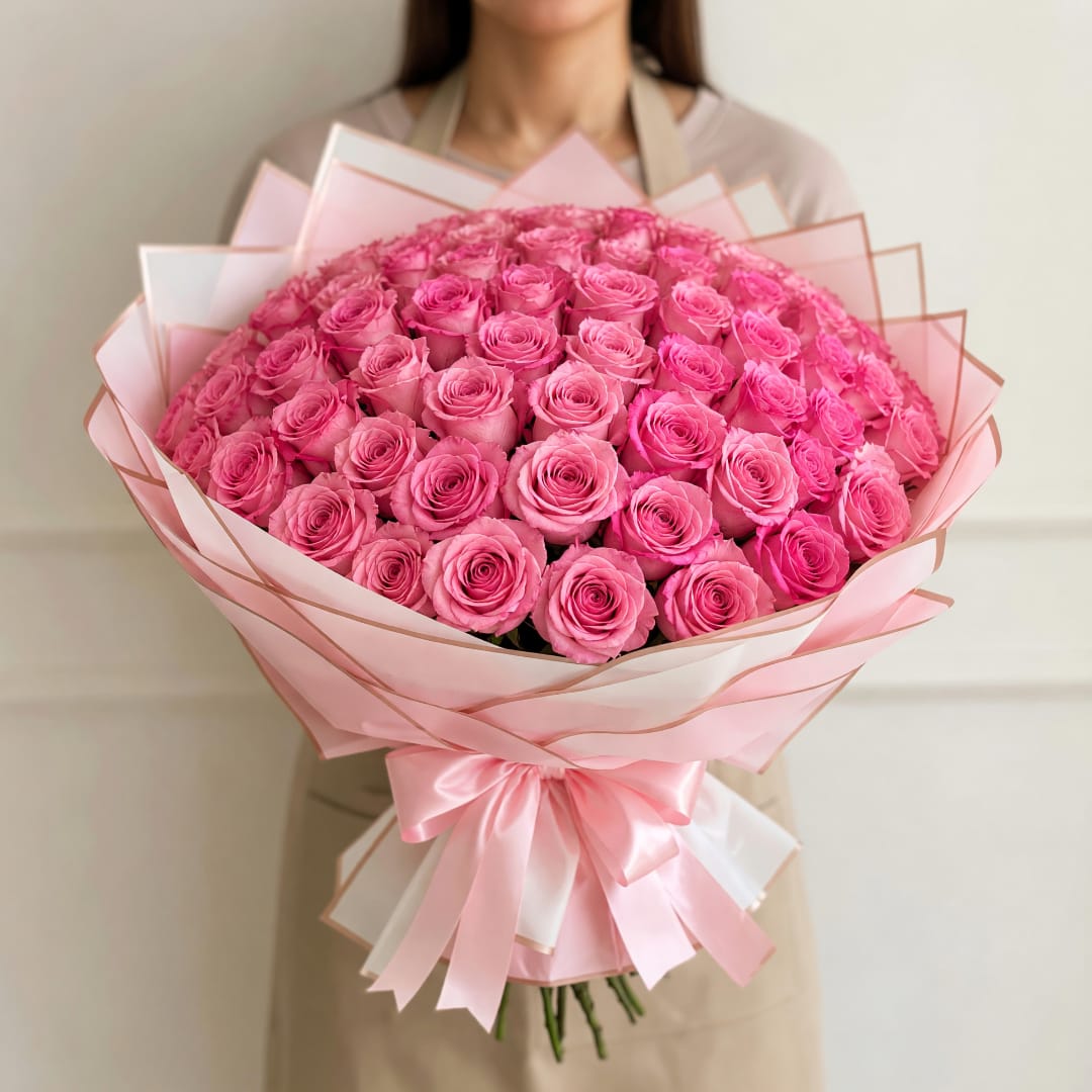 Large bouquet of pink roses wrapped in pale pink paper with a satin bow