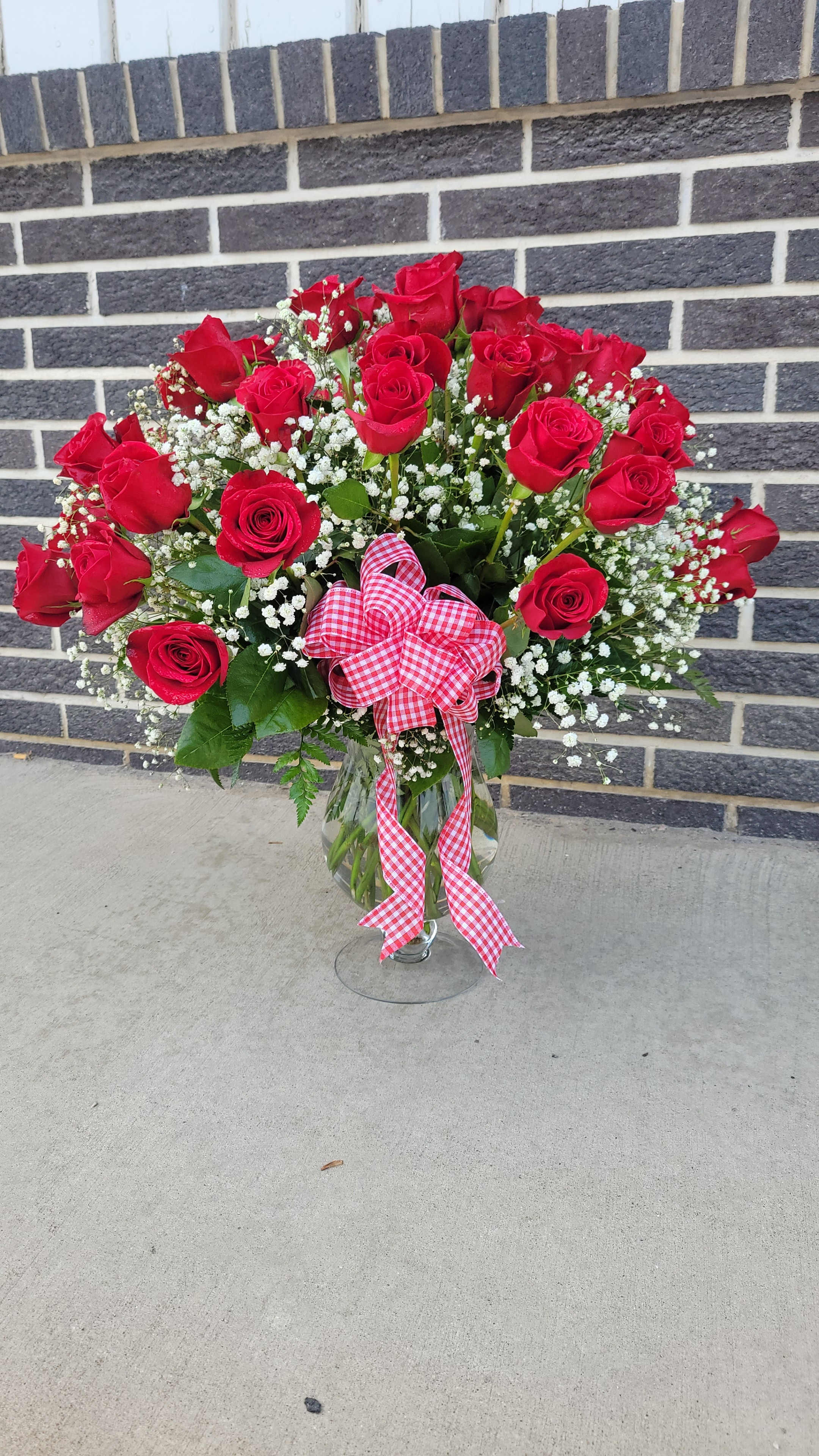 Bouquet of red roses in a glass vase with a gingham ribbon