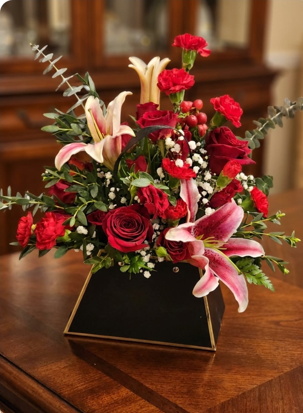 Red roses and pink lilies in a black geometric vase