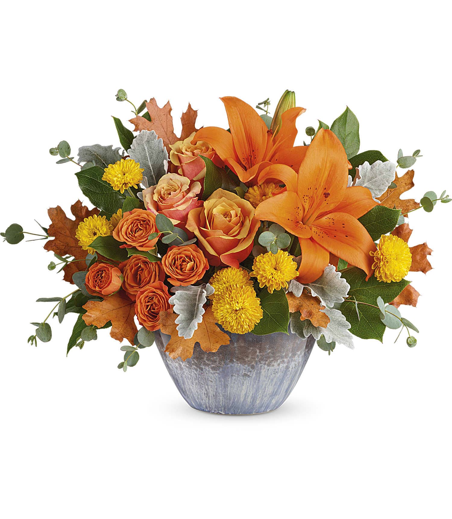 Teleflora's Golden Bounty Centerpiece - Make the season shine with this golden fall bounty of roses and lilies, arranged in a gorgeous oven-to-table ceramic bowl. It's finished with an eye-catching artisanal glaze in shades of steel blue--the perfect mix of pretty and practical!  This arrangement features orange roses, orange spray roses, orange asiatic lilies, yellow cushion spray chrysanthemums, dusty miller, lemon leaf, and parvifolia eucalyptus. Delivered in Teleflora's Bountiful Blessings Bowl. Approximately 17 1/4" W x 12" H