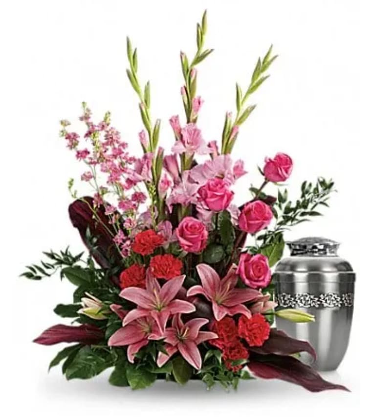 Pink roses and lilies arranged beside a silver urn