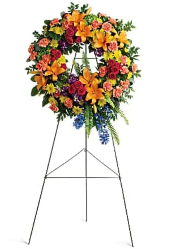 Large floral wreath on a standing easel with orange, pink, yellow, and blue flowers