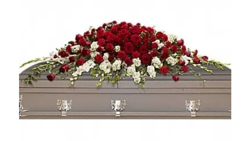 Red and white floral casket spray on a gray casket