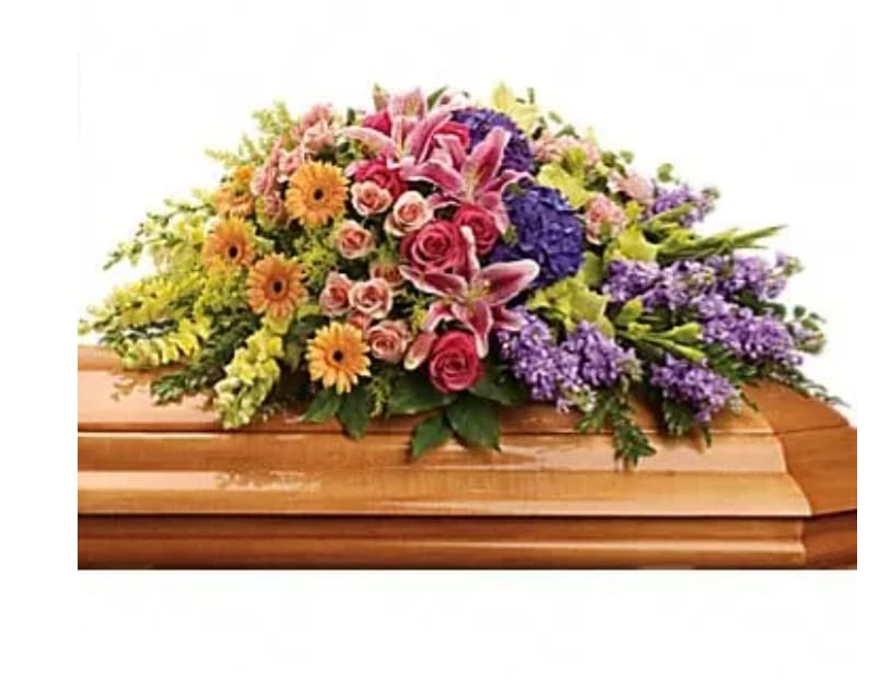 Colorful floral spray on a casket with pink, purple, and yellow blooms