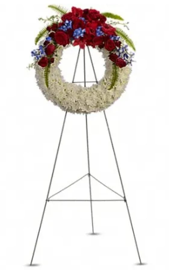 Standing funeral wreath with red and white flowers and blue accents