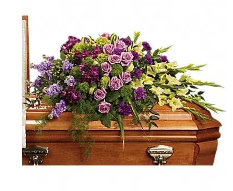 Purple and green floral spray on a wooden casket