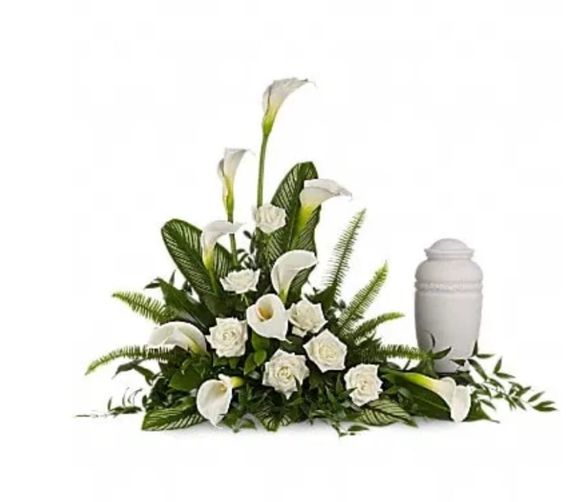 White calla lilies and roses arranged beside a white urn