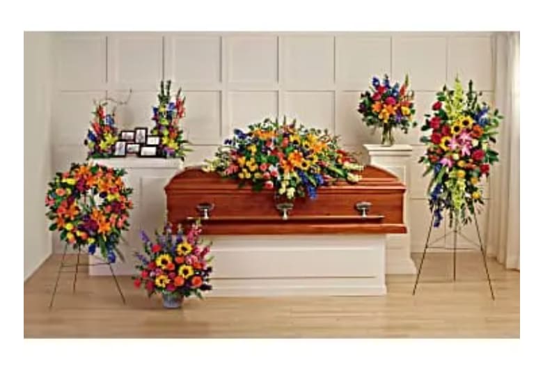 Colorful funeral floral arrangements around a wooden casket