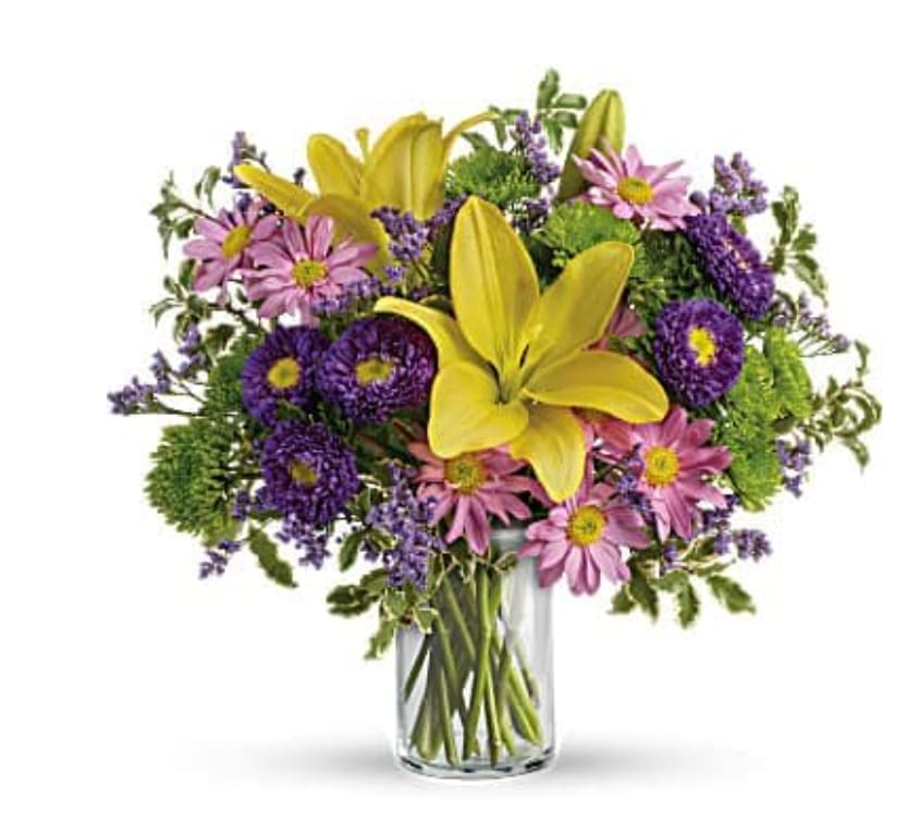 Yellow lilies and purple daisies in a clear glass vase