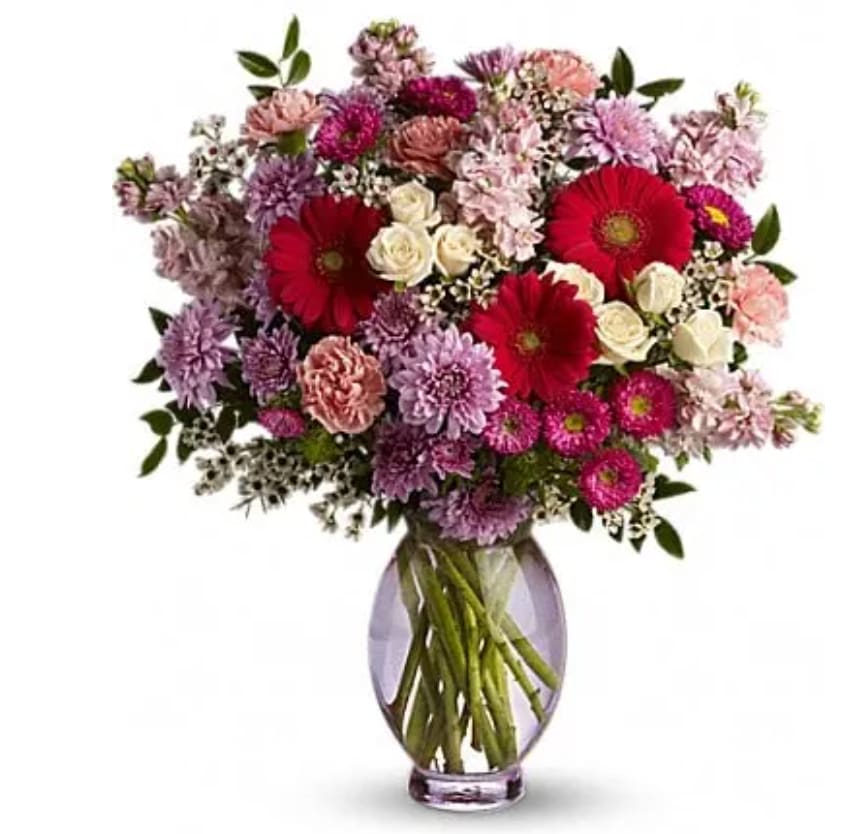 Mixed pink and purple bouquet with red gerbera daisies in a glass vase