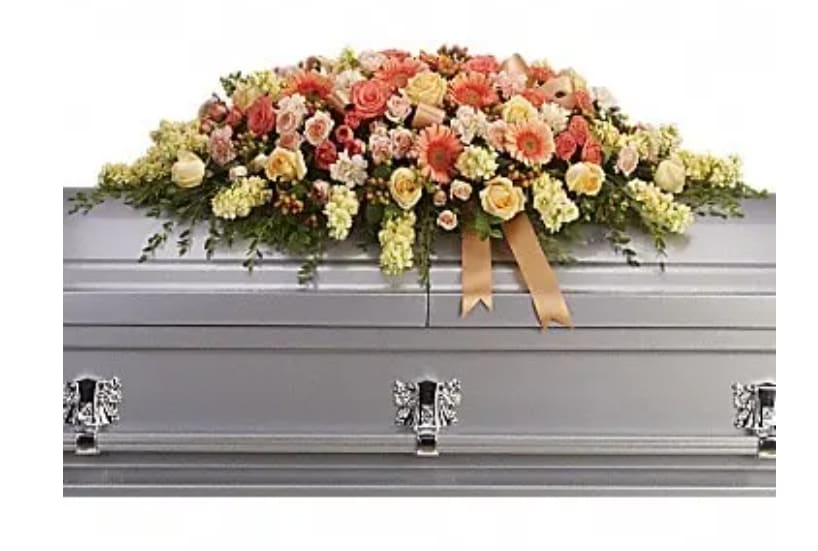 Floral casket spray with peach, pink, and cream flowers
