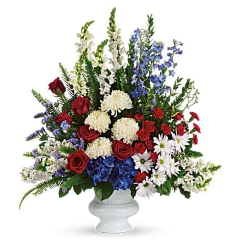 Red roses, white flowers, and blue blooms in a white vase