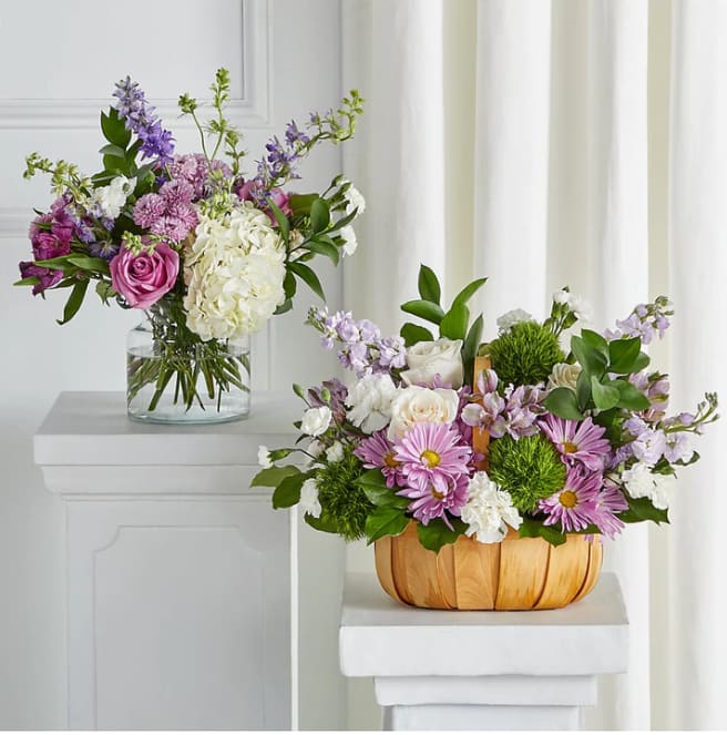 Two floral arrangements with pink, white, and purple blooms, one in a glass vase and one in a wooden basket