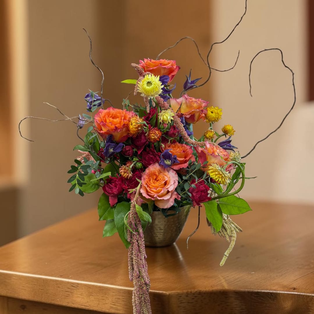 Colorful mixed flower arrangement in a small metal vase