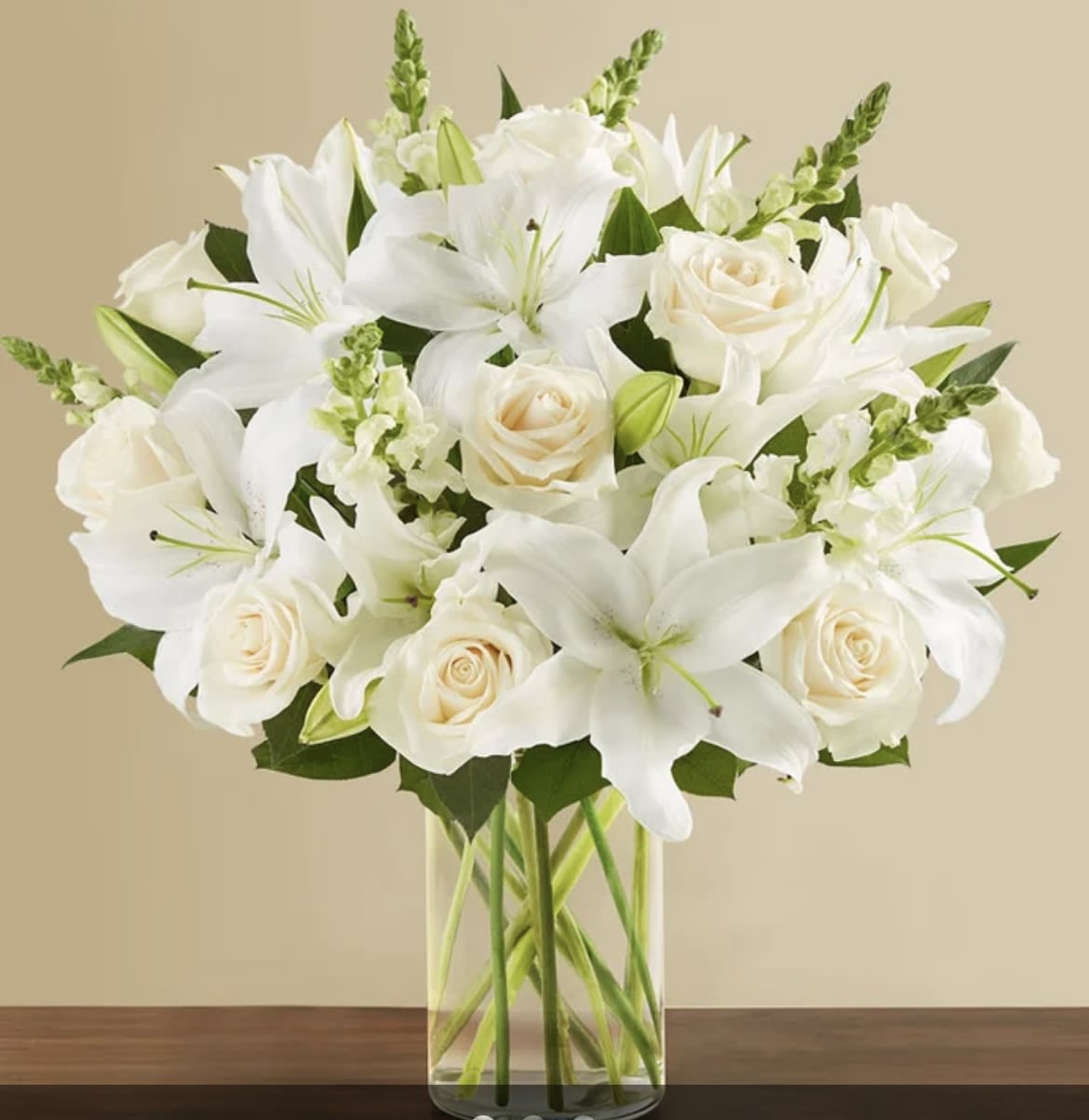 White lilies and cream roses in a clear glass vase
