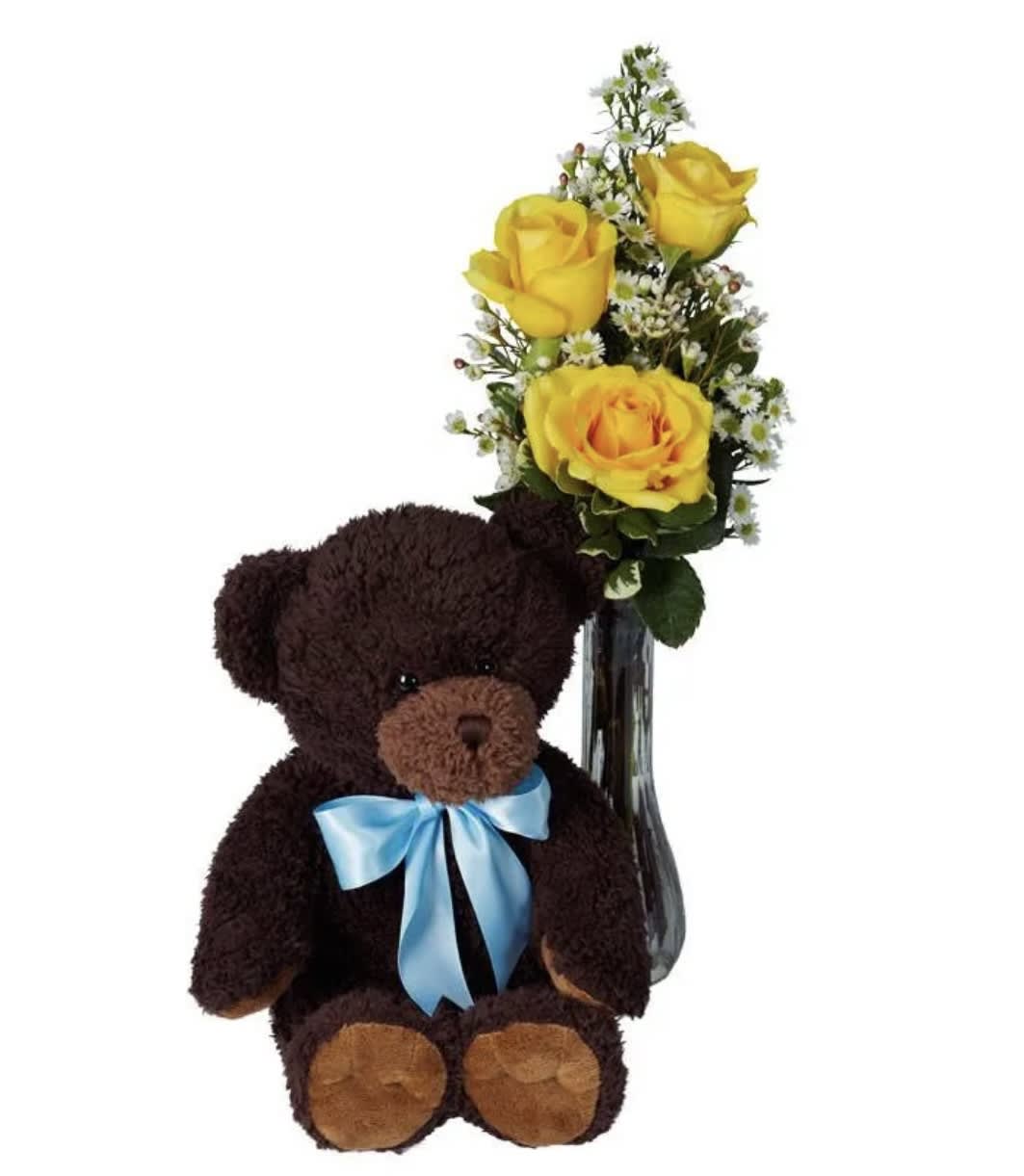 Teddy bear beside yellow roses in a glass vase