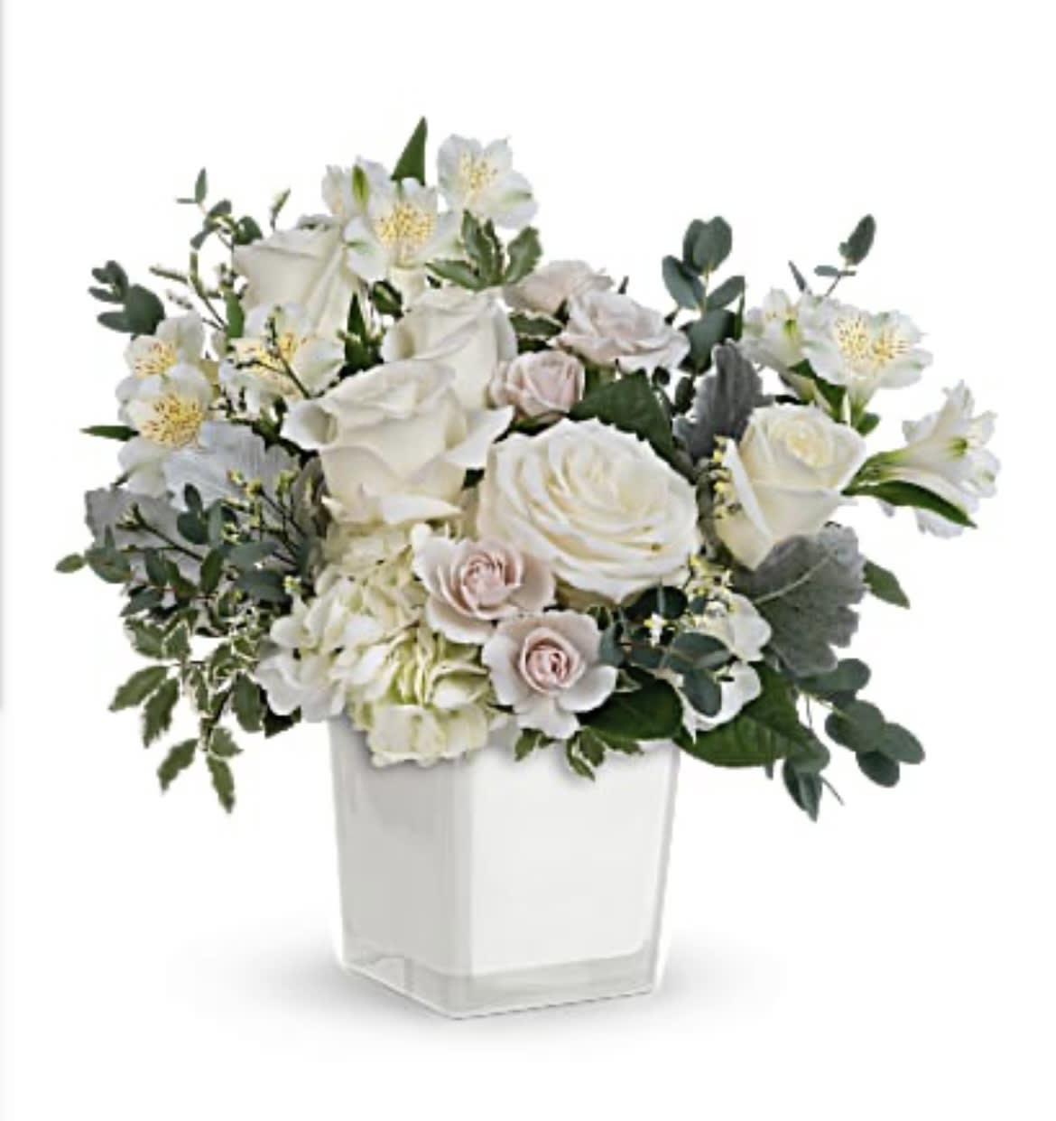 White roses and pale blooms arranged in a clear square vase