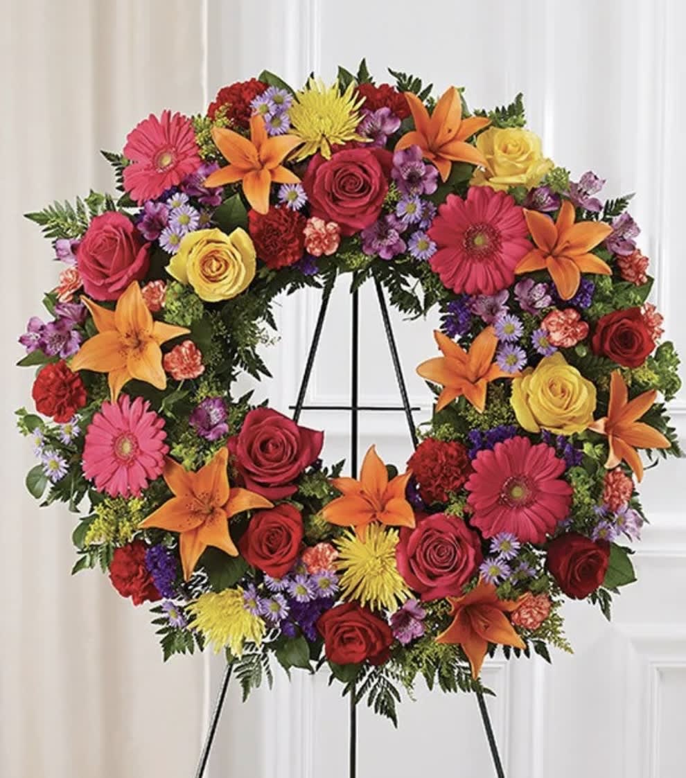 Colorful floral wreath on a black easel with roses, lilies, and daisies
