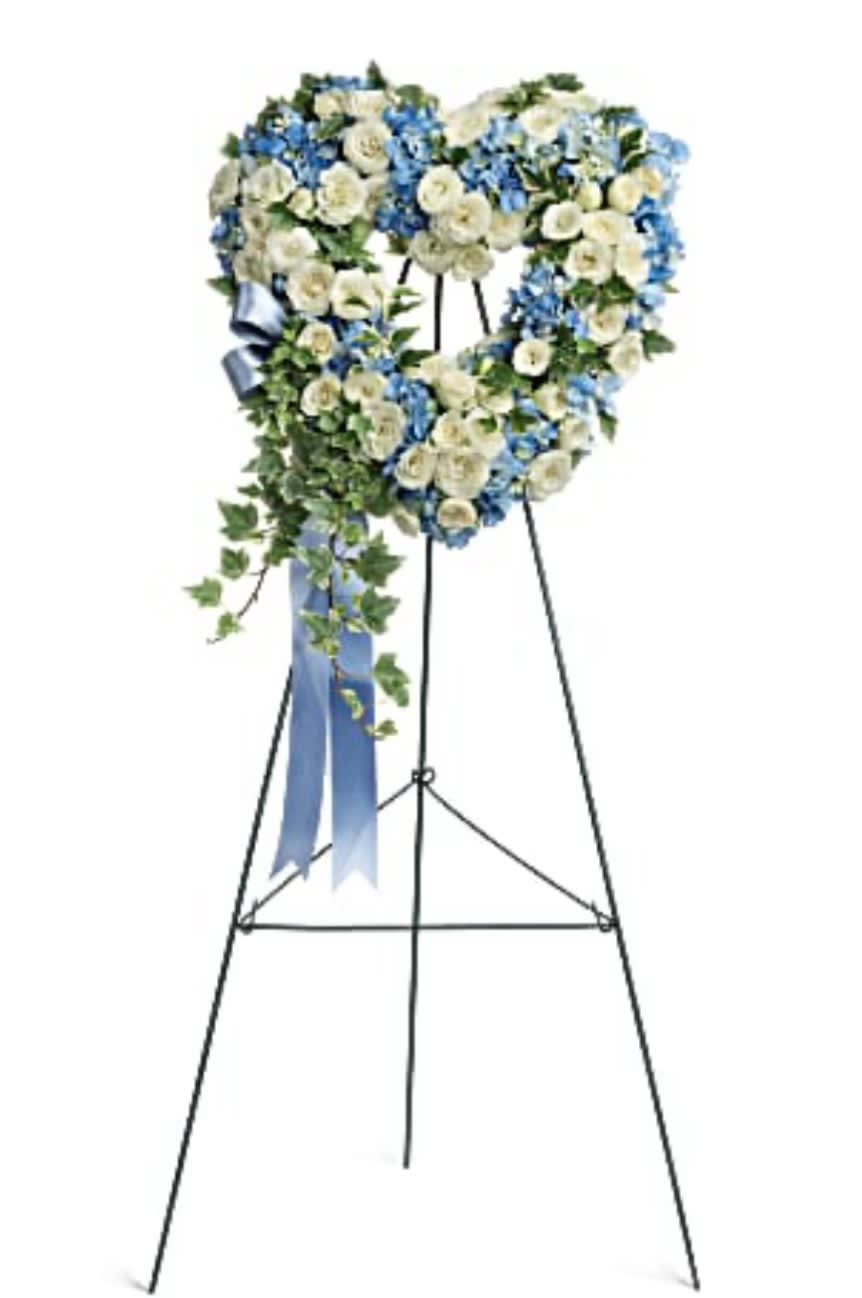 Heart-shaped floral wreath on a standing easel with blue and white flowers