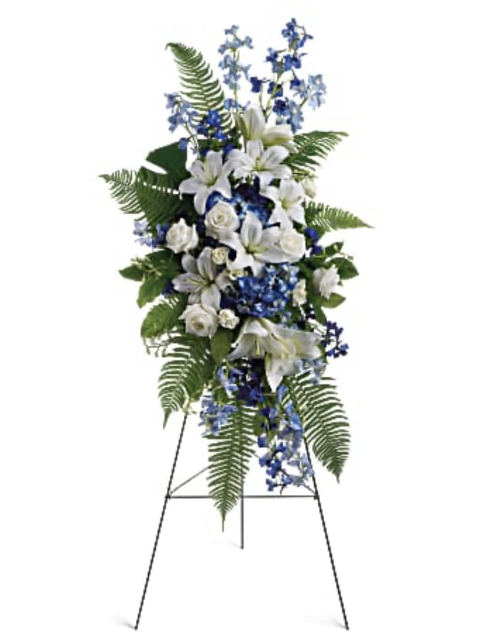 Standing floral spray with white lilies and blue flowers on an easel