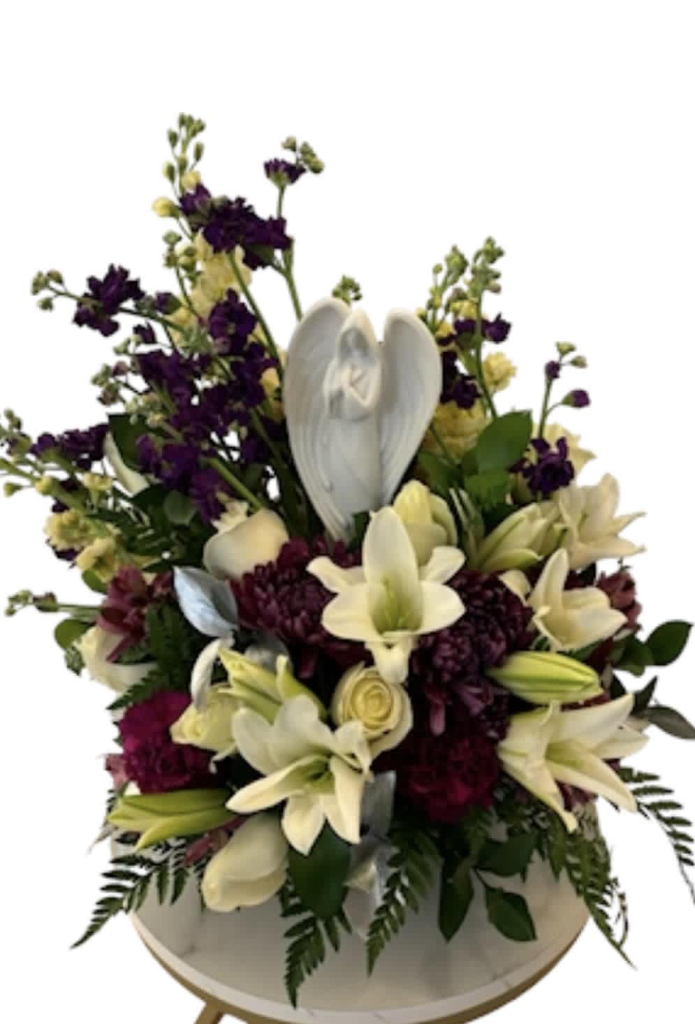 White lilies and purple flowers arranged in a round vase with a white angel ornament